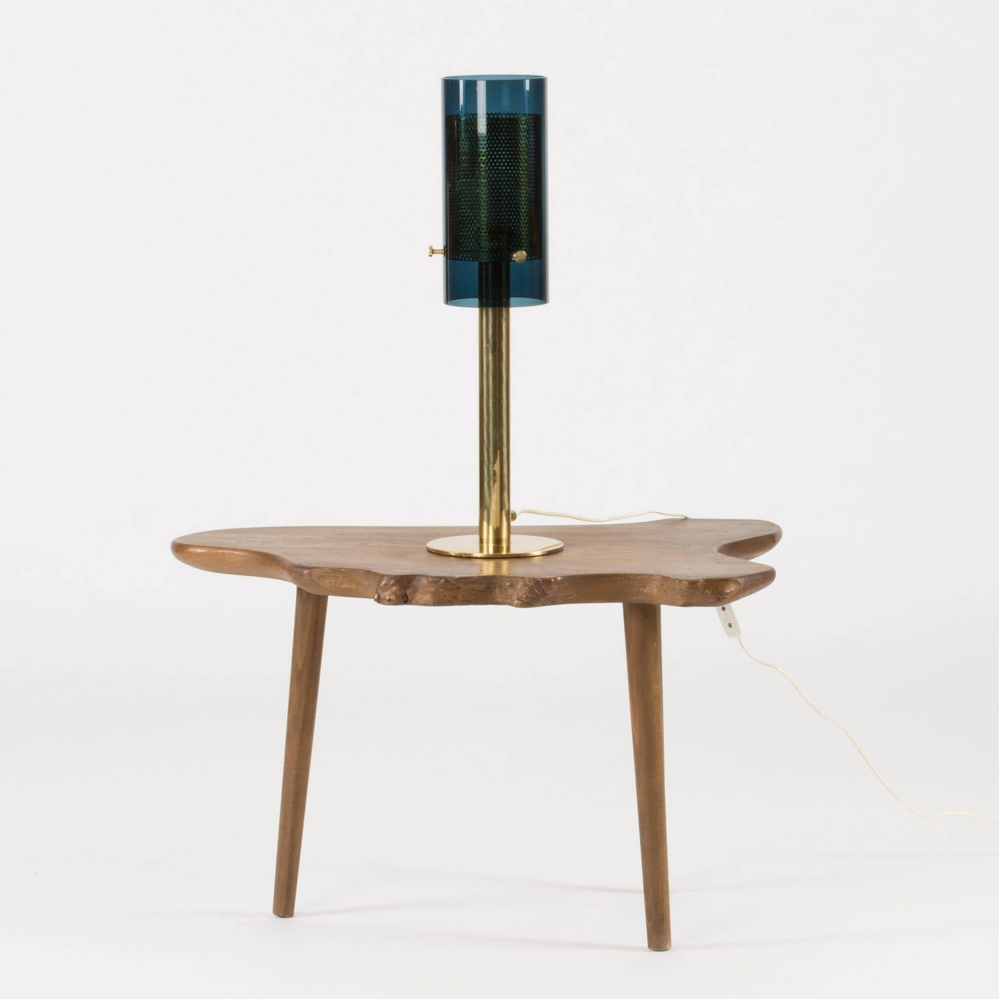 Amazing brass table lamp by Hans-Agne Jakobsson. Tall and heavy with a cylindrical petrol blue glass shade around an inner shade made from perforated brass. The shades are attached with large decorative brass screws.