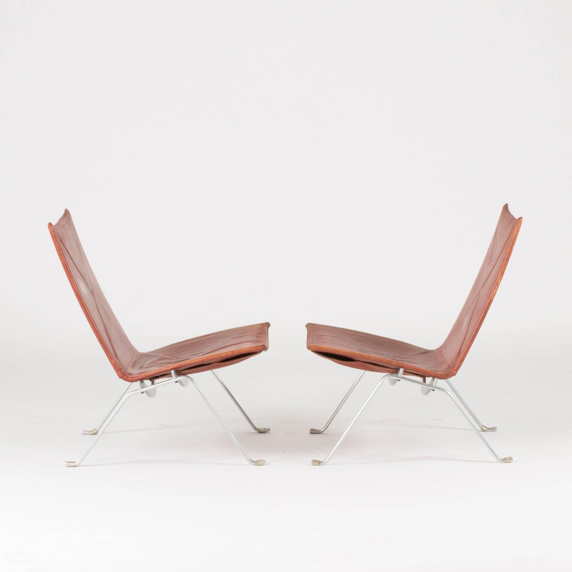 Pair of “PK 22” lounge chairs by Poul Kjaerholm, made from brushed steel and rust colored leather. Made by original producer E. Kold Christensen. A repair has been made to the leather on one corner of one of the chairs.