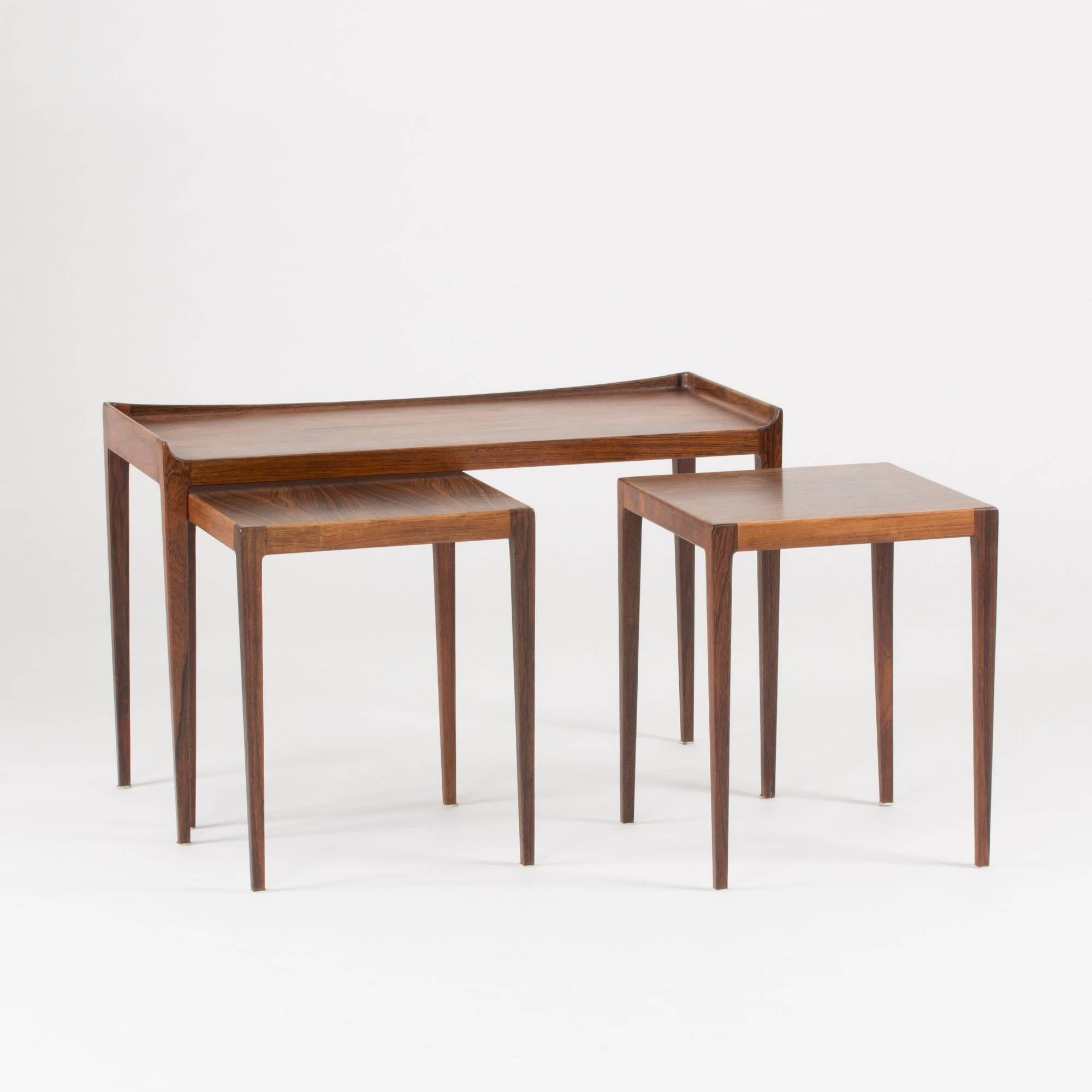Elegant, slender rosewood nesting table by Kurt Østervig with two square tables nested under a taller rectangular one. A beautifully sculpted rim frames three sides of the upper table.