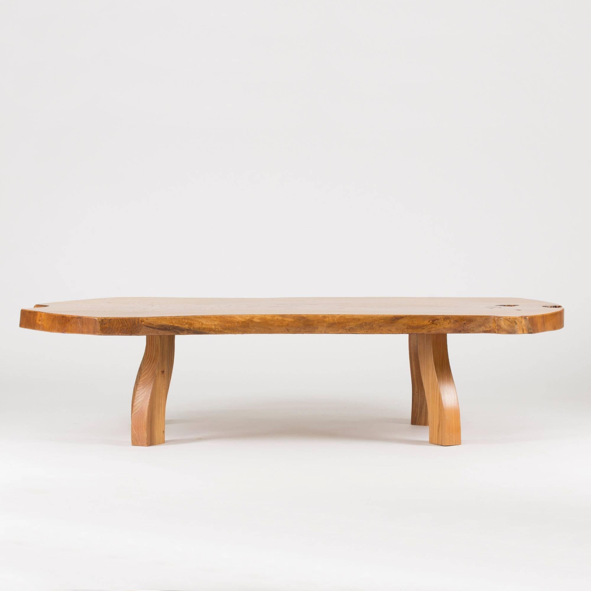 Amazing pine coffee table from C.A. Beijbom. Made from a large, thick pine slab with brutish, sculpted legs. Lively wood grain and accentuated knots at the far edges.
