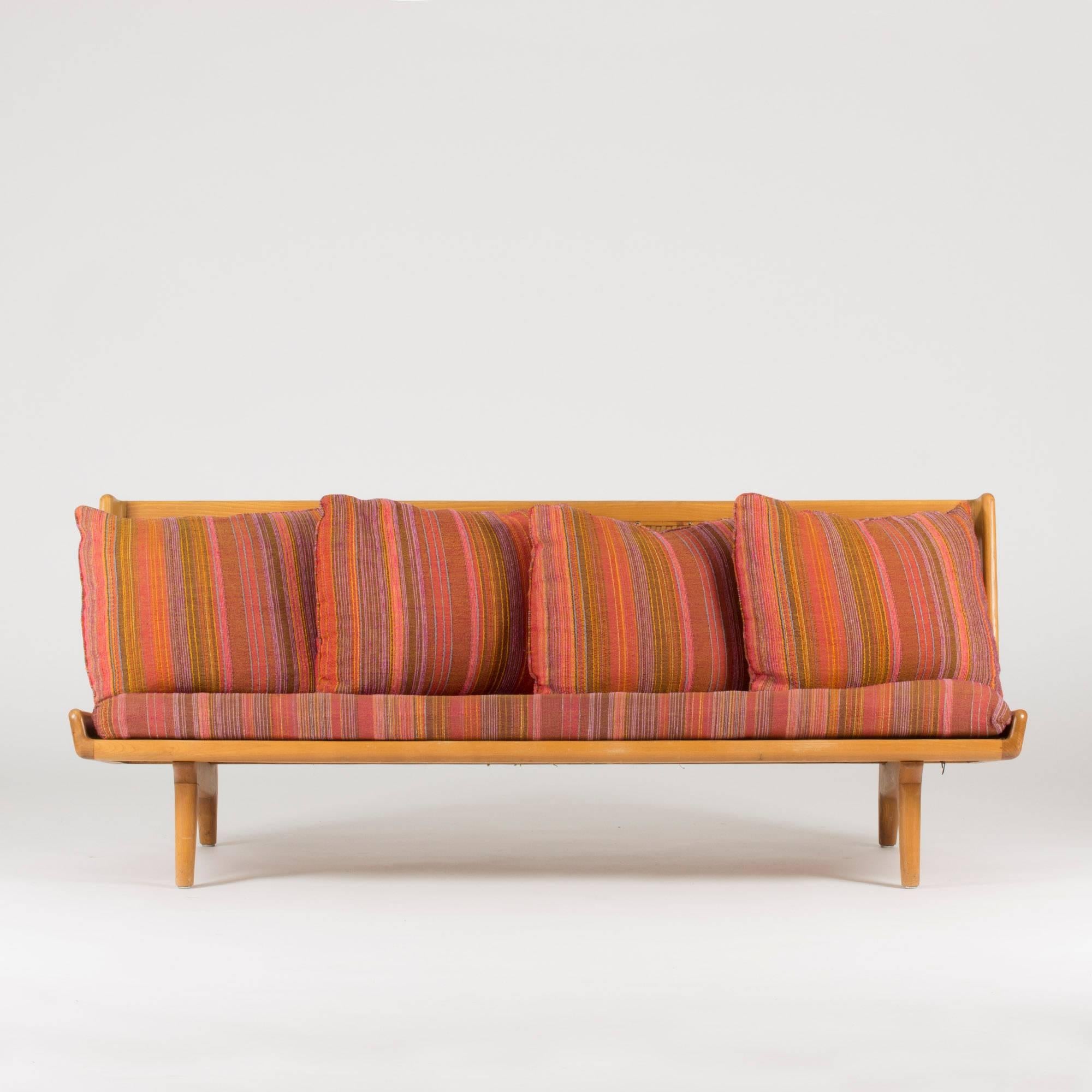 Sofa by Gustaf Hiort af Ornäs, made from beech with sculptural details. The amazing leather webbing backrest makes this sofa a real room jewel. Pillows and seat with beautiful, original wool fabric. Minor repairs to the leather webbing.