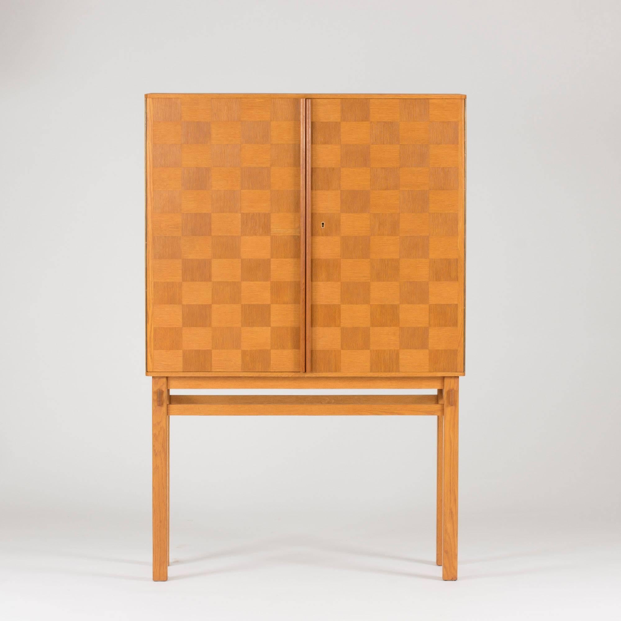 Swedish cabinet masterpiece, made by an unknown master carpenter in the 1950s. Made from oak with a simple and so striking checkered pattern. The squares are arranged so that the direction of the wood grain alternates. The doors have brass hinges