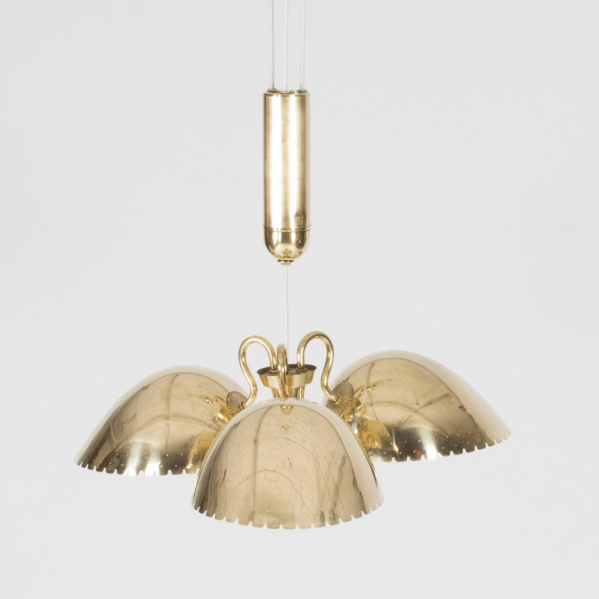 Luxurious brass ceiling lamp by Carl-Axel Acking with three large sconces and a heavy solder hiding the wiring. The sconces have square scalloped rims and are perforated around the bottom edges with small holes.

In 1939, Carl-Axel Acking