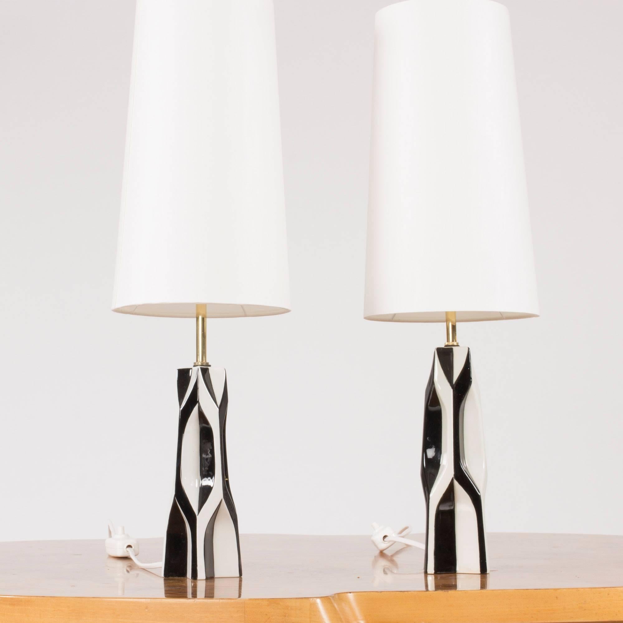 Pair of amazing stoneware table lamps by Carl-Harry Stålhane. Graphical, sculptural bodies with slightly altering heights which is evened out by the height of the brass handles. Striking black and white decor.