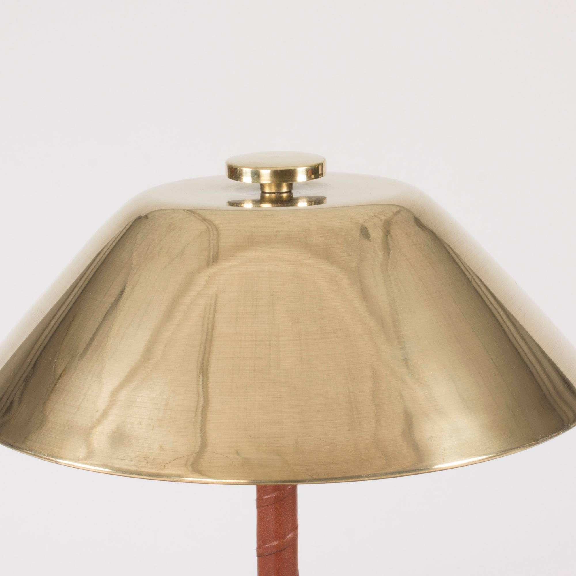 Very elegant table lamp by Einar Bäckström, made of brass with an appealing, disc decoration on top. Handle wound with brown leather.