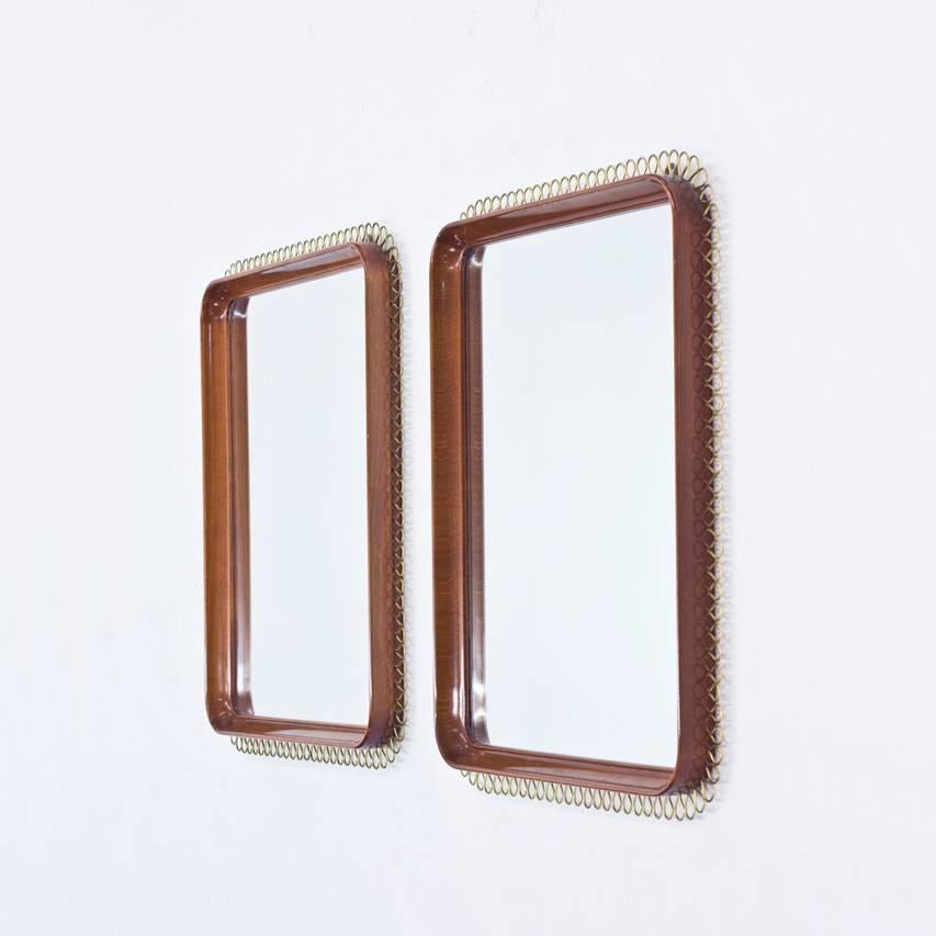 Pair of beautiful wall mirrors with mahogany frames and decorative lines of wavy brass wire. Elegant style in the manner of Josef Frank.