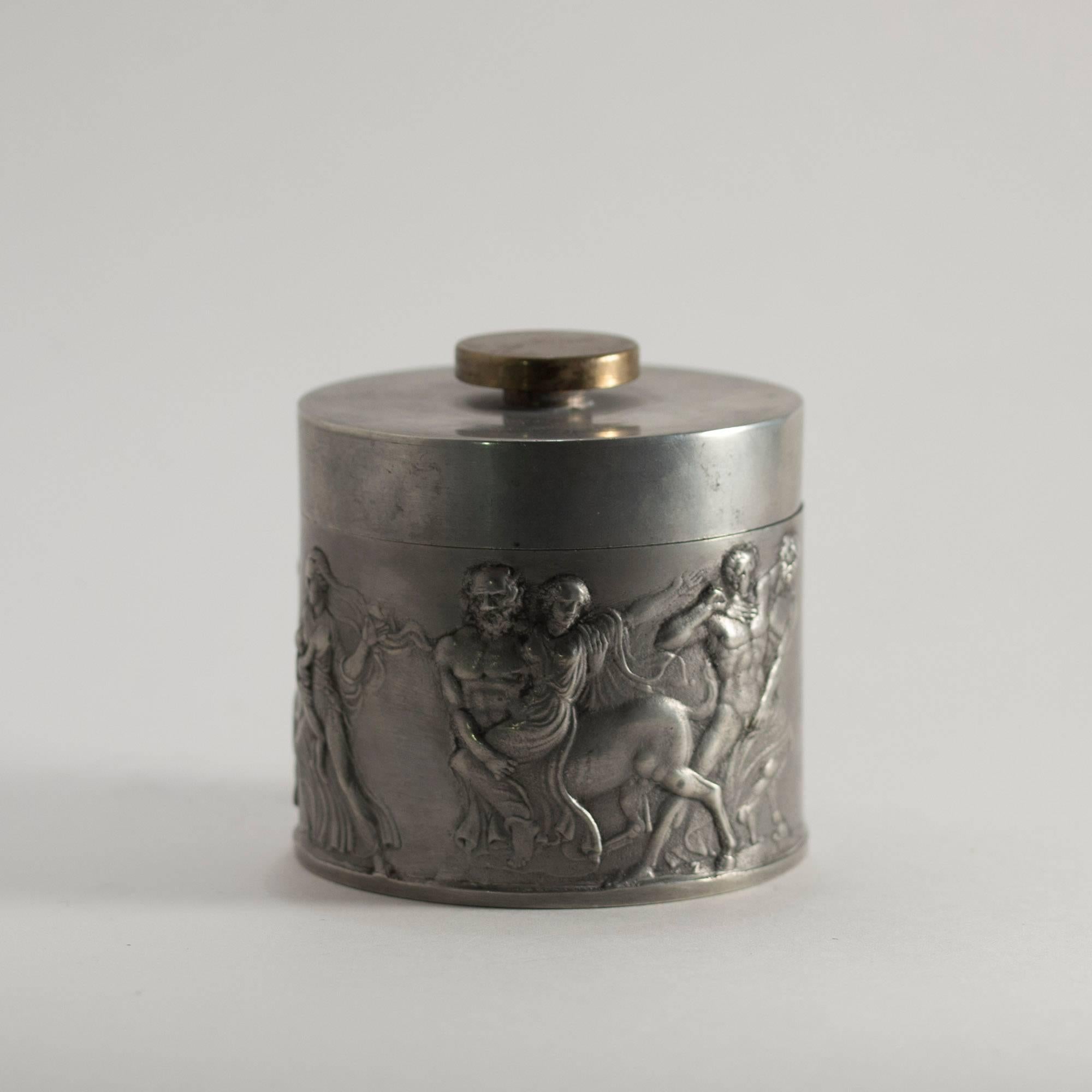 Pewter jar with brass knob and inset in four sections. Designed by Herman Bergman, who was the founder of Herman Bergman's Fine Art Foundry, purveyor to the Royal Court. A dramatic scene with centaurs, a warrior and a woman with a baby is depicted