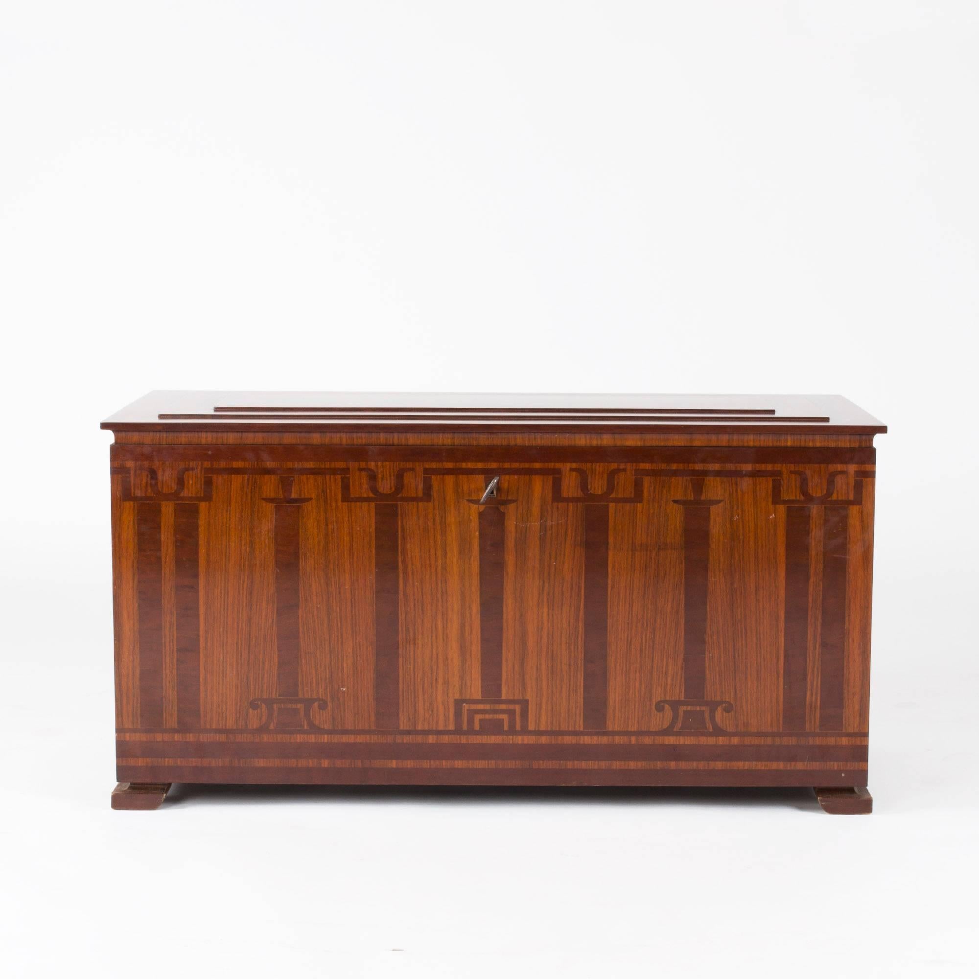 Very elegant chest designed by Carl Malmsten and executed at NK in rosewood and stained birch. Inlays in a pattern of Art Deco style columns. The lid has a slight build up design with the wood grain laid in a striking striped pattern. Black