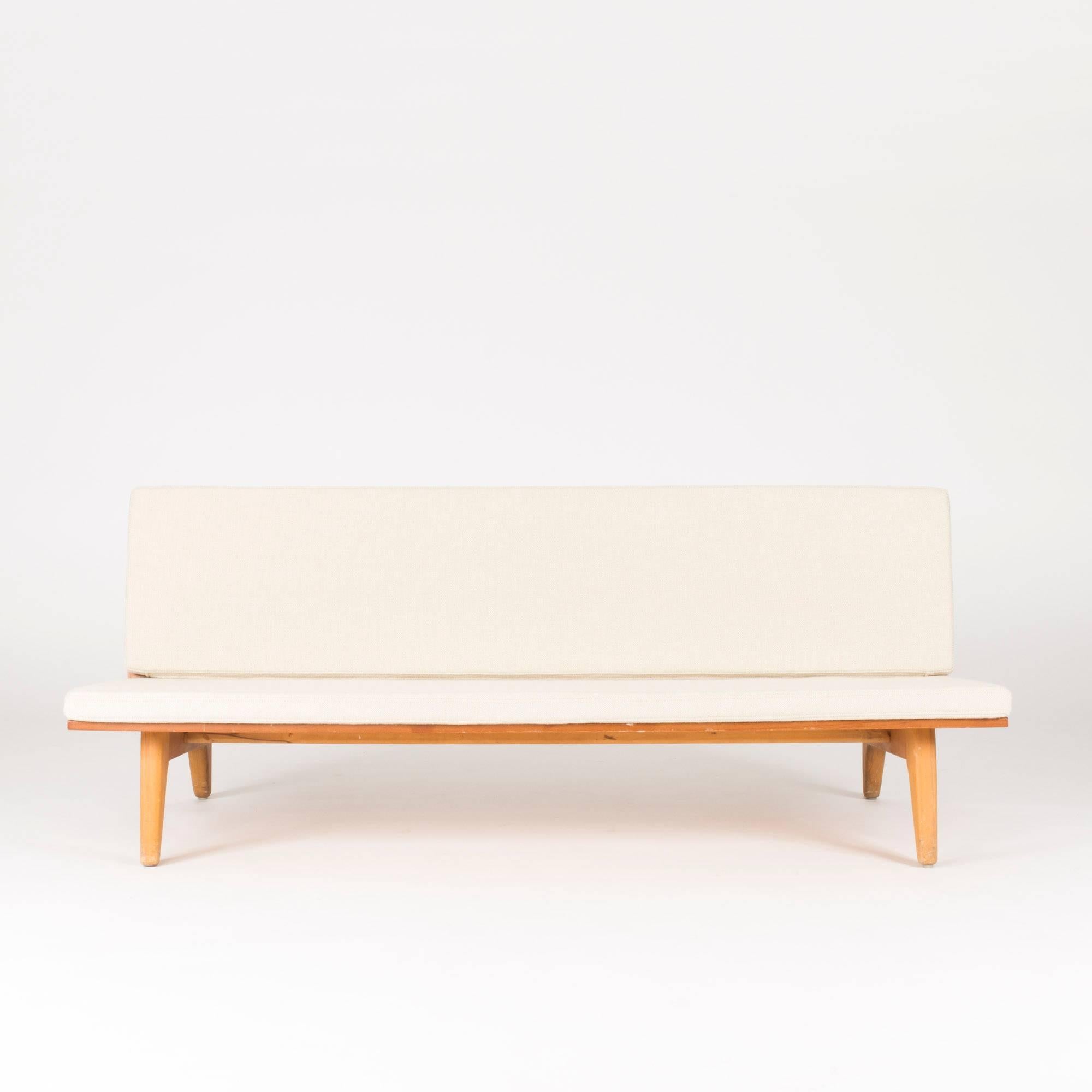 Rare teak sofa designed by Gustaf Hiort af Ornäs and produced by Gösta Westerberg. The sofa is made from two teak rectangles forming the seat and back, on sculpted legs. The wool-clad cushions are removable. A pair is available.