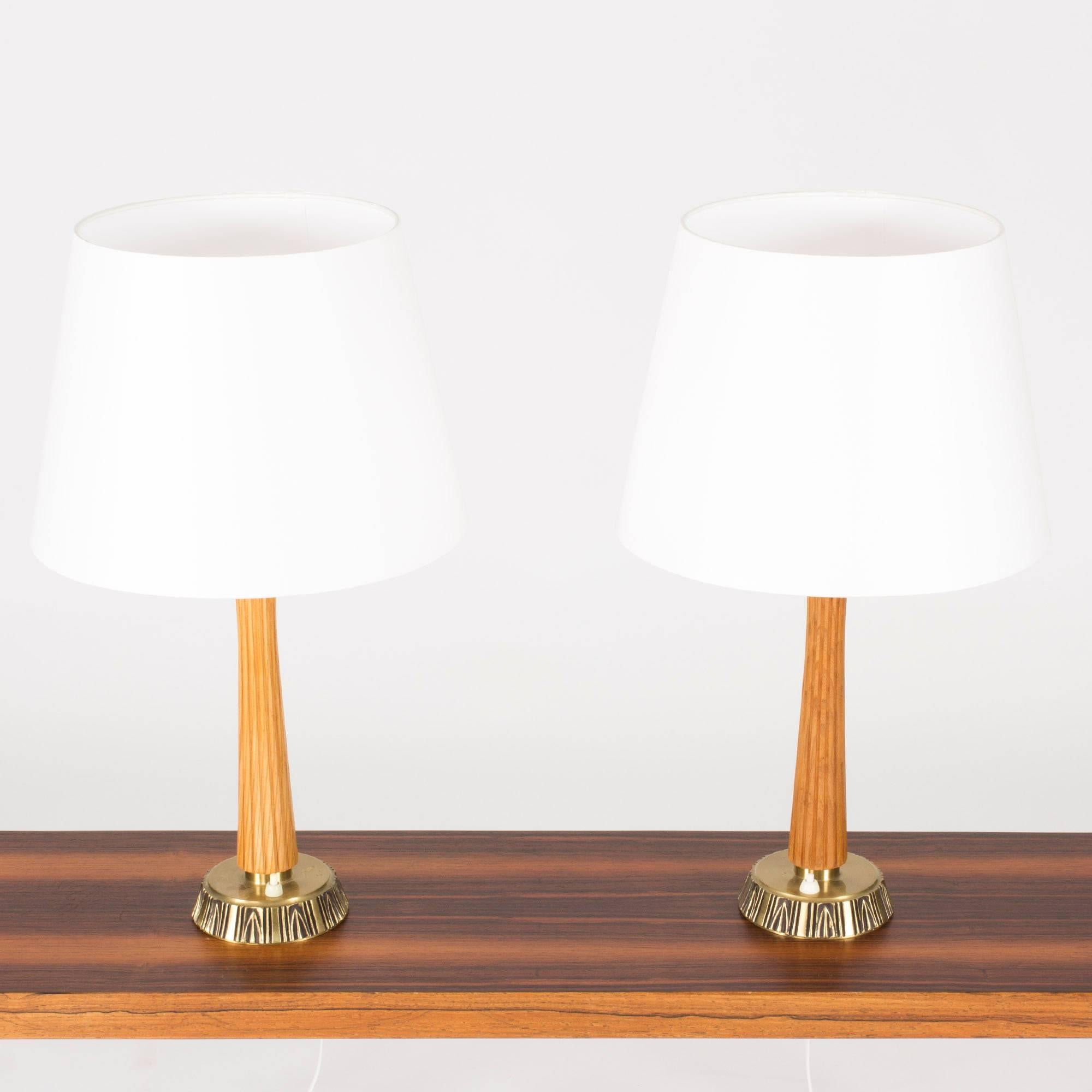 Pair of table lamps by the sculptor Sonja Katzin for ASEA. Handles made from teak with a carved pattern of vertical stripes, bases made from brass with a pattern with ethnic influences.