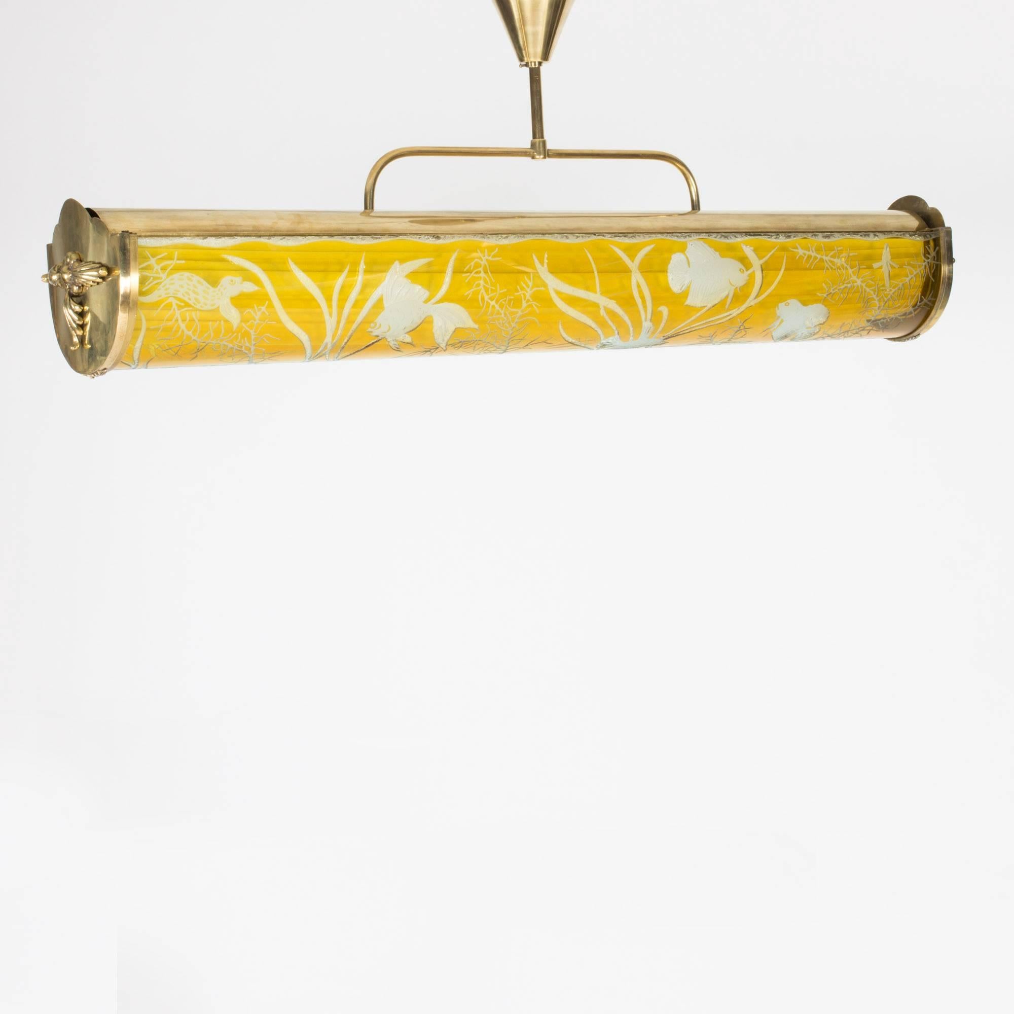Incredibly beautiful ceiling light, made in Sweden in the 1940s. Made of brass with ornamental decorations on the ends and yellow glass that has a cut underwater motif. The top rims of the glass have a subtle wavy shape along the length where the