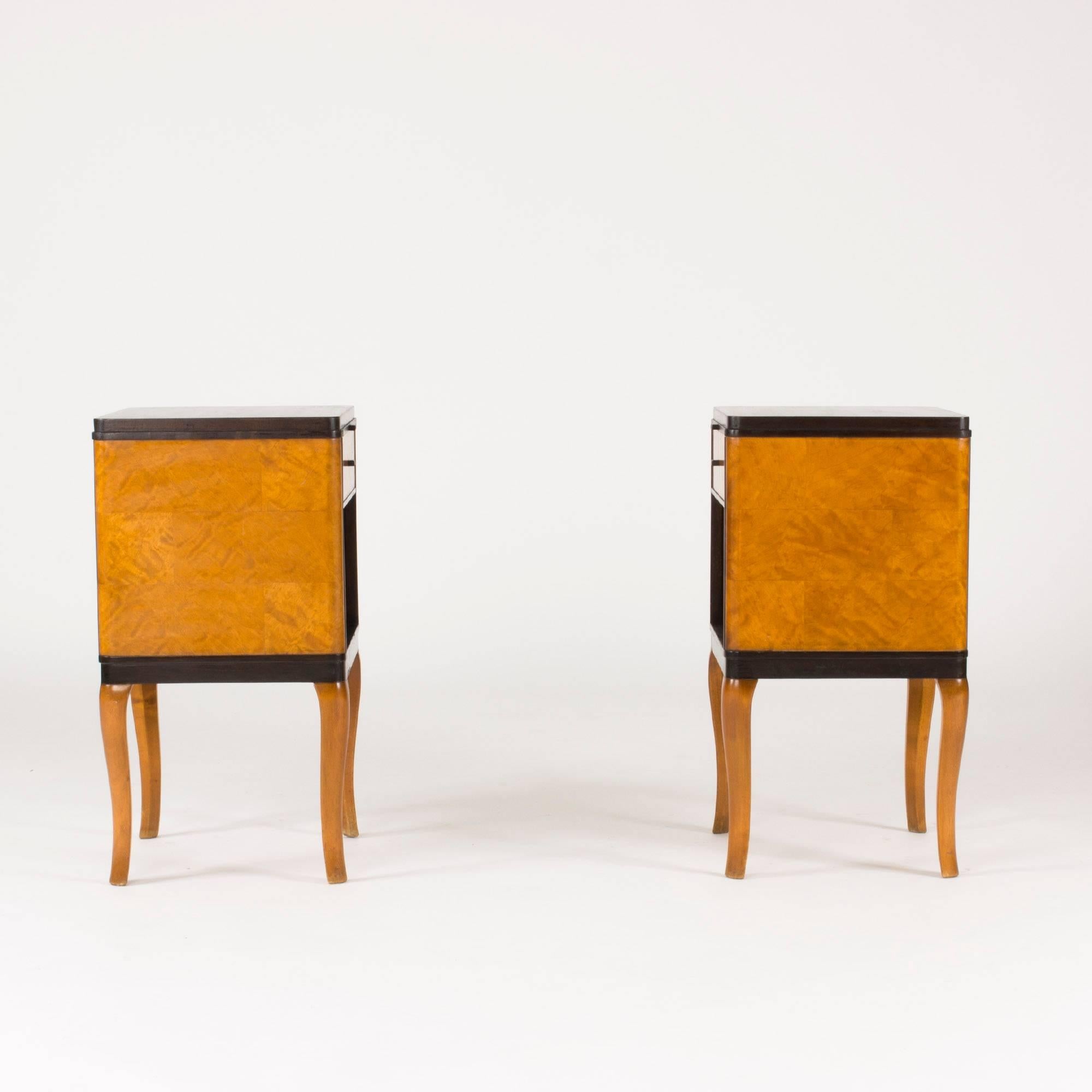 Pair of beautiful bedside tables by Carl Malmsten, model named “Haga”. Made in alder root and stained birch. On the sides the wood is layered in a checkered pattern. Curved legs connoting neoclassicism.