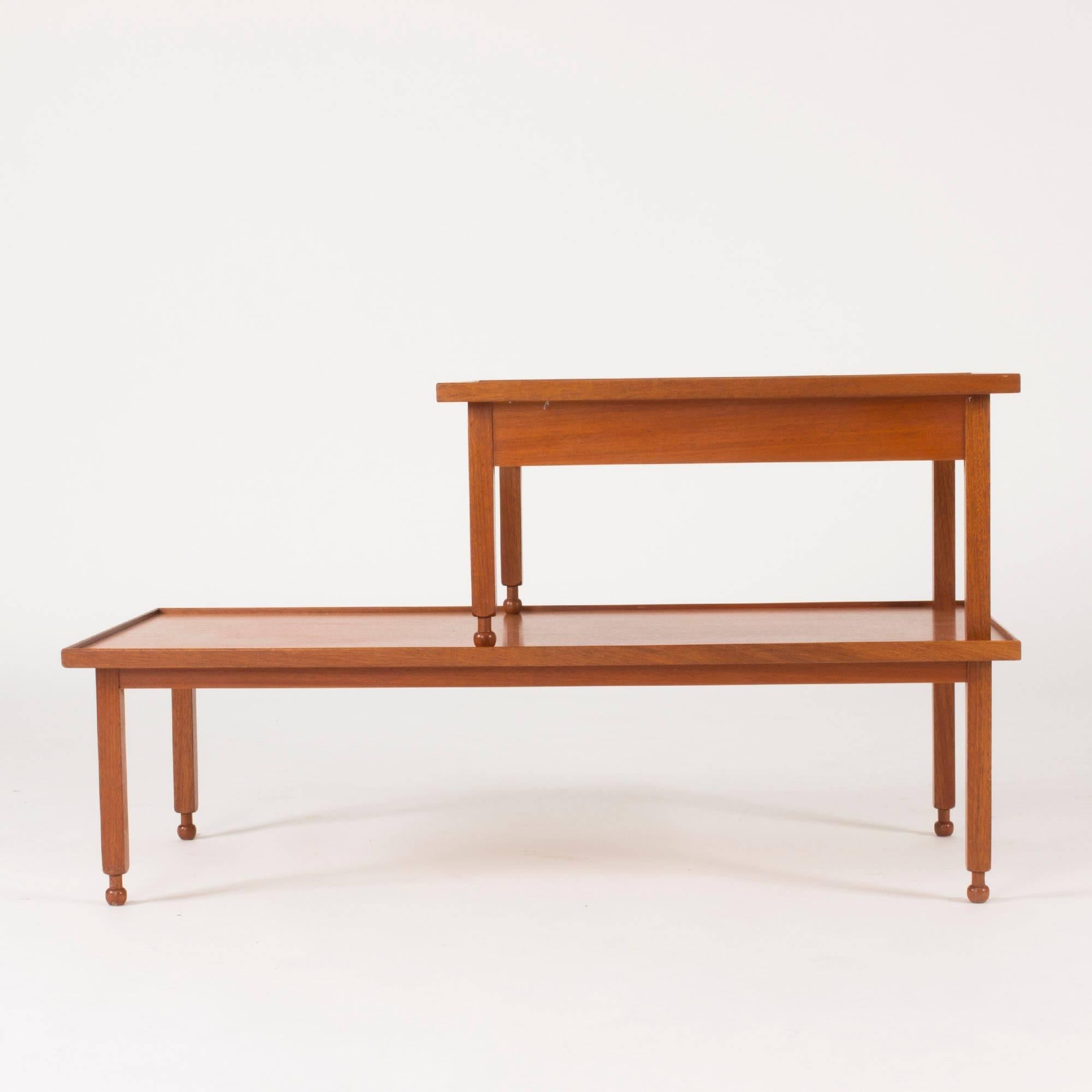 Beautiful, innovative side table by Josef Frank, made in mahogany. The upper section has a drawer with a brass handle. Lovely sculpted feet and rims framing the table tops.