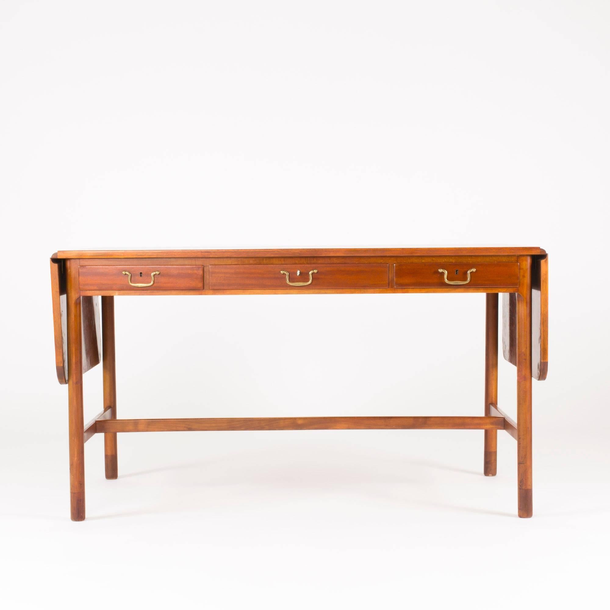 Very elegant mahogany desk by Josef Frank. Drop leaves on the sides make it possible to extend the length to 202 cm. Three drawers with brass handles.