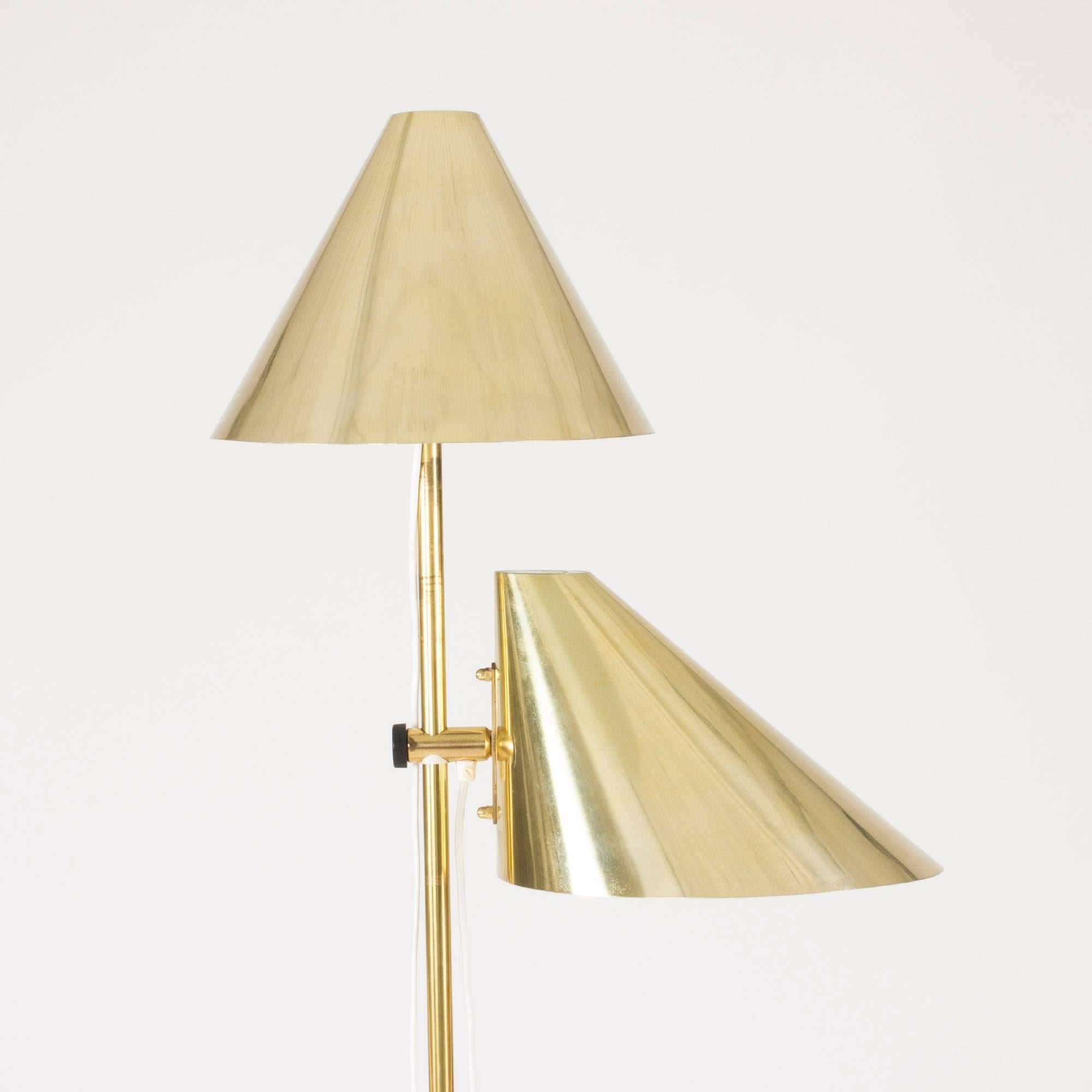 Oh so cool brass floor lamp by Hans Agne Jakobsson with two shades at different heights. The wiring runs along the lamp pole and is fastened to it with little black clamps. Heavy, wide brass base.