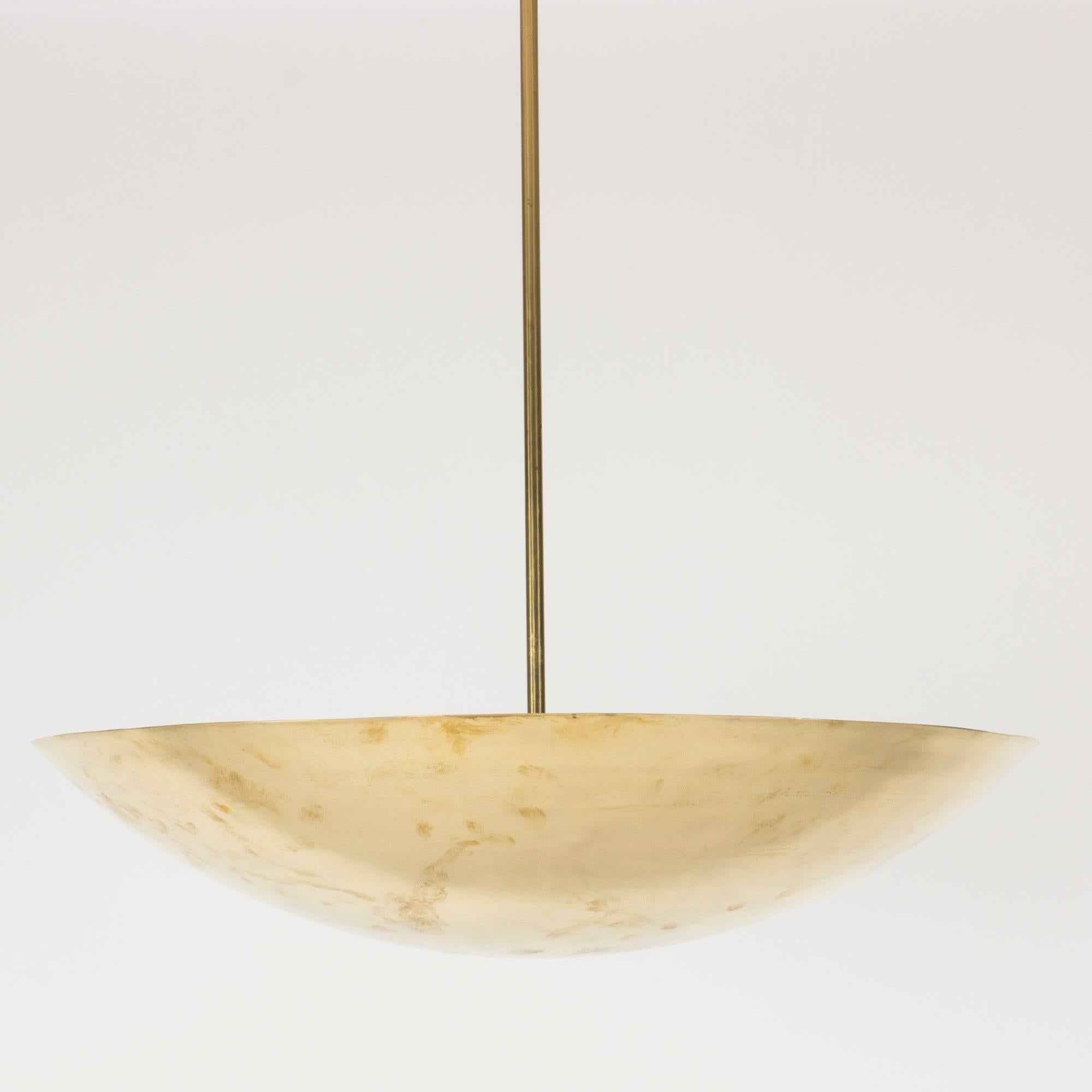 Striking brass ceiling lamp, in a clean, spherical shape that directs the light upwards. Beautiful, shining brass with a subtle hand-finished look. Brass pole with a loop for suspension at the end.