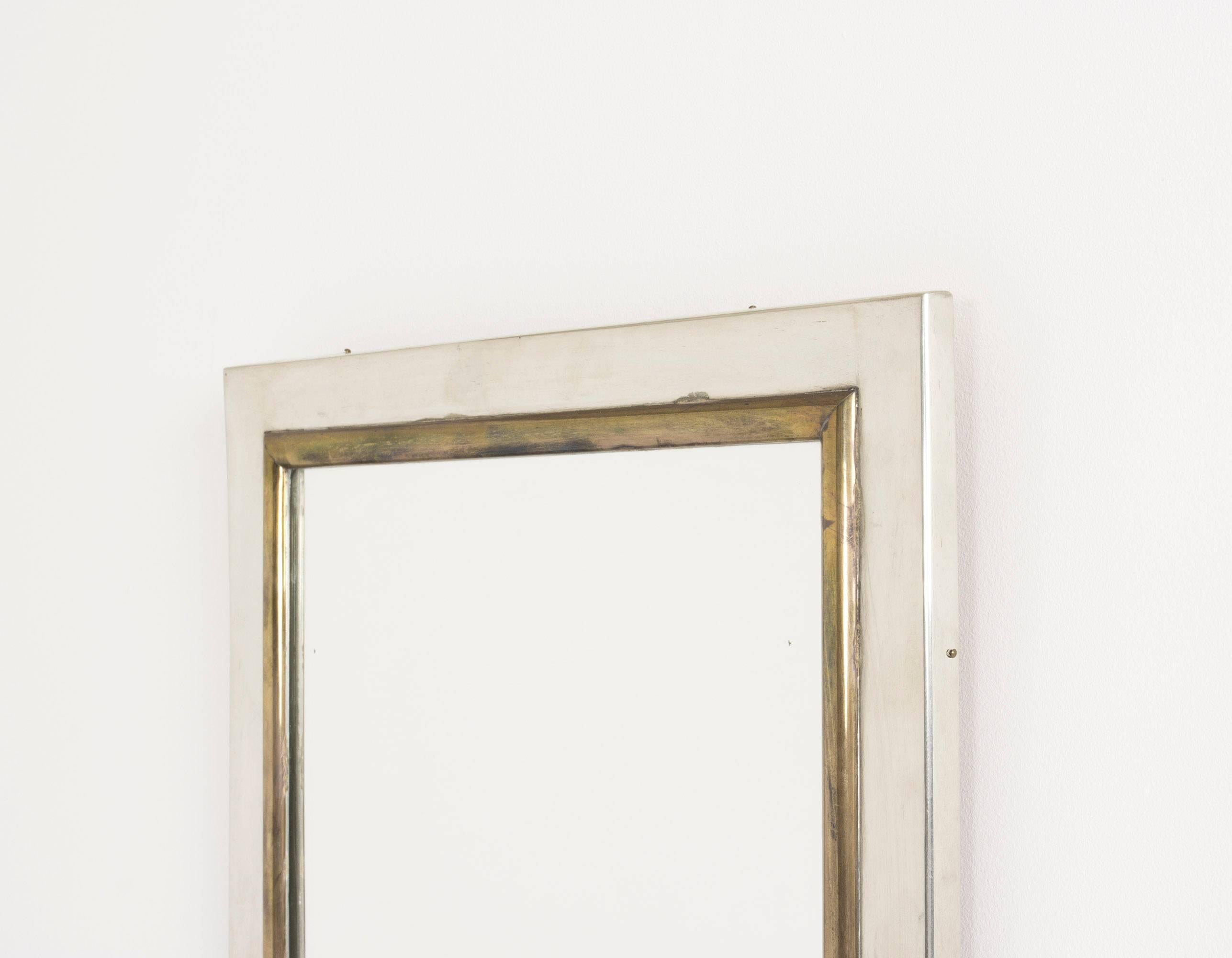 Striking wall mirror by Estrid Ericson with a frame completely dressed in pewter. The inner margins of the mirror are framed with brass for a warm contrast.