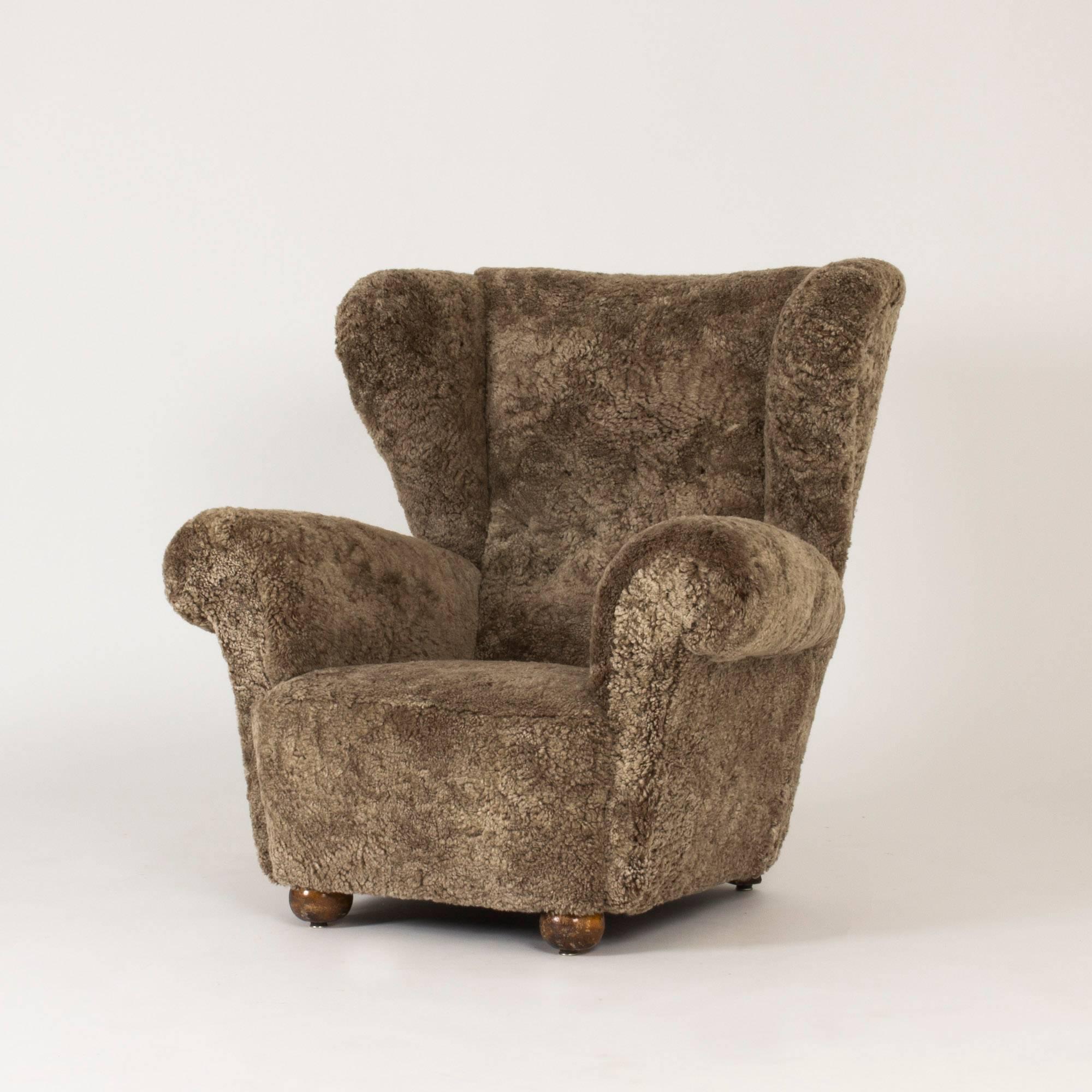 Oversized, incredibly cozy Swedish 1930s lounge chair, reupholstered with sheepskin. Made by an unknown master carpenter. The chair has exaggerated lines and bold angles, giving it a very cool expression. Round wooden feet.
