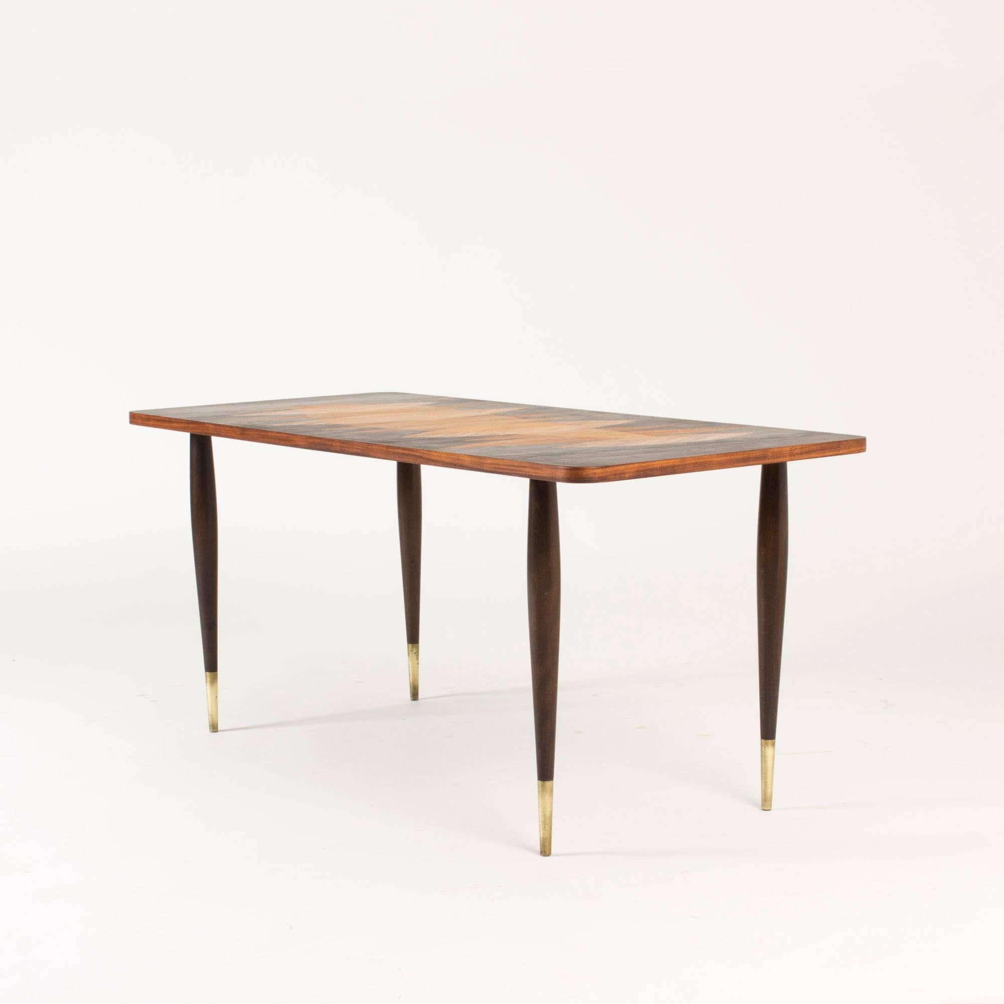 Rosewood coffee table by Bröderna Miller with striking inlays in a pattern of leaves in a contrasting nuance of wood. Legs with brass feet.