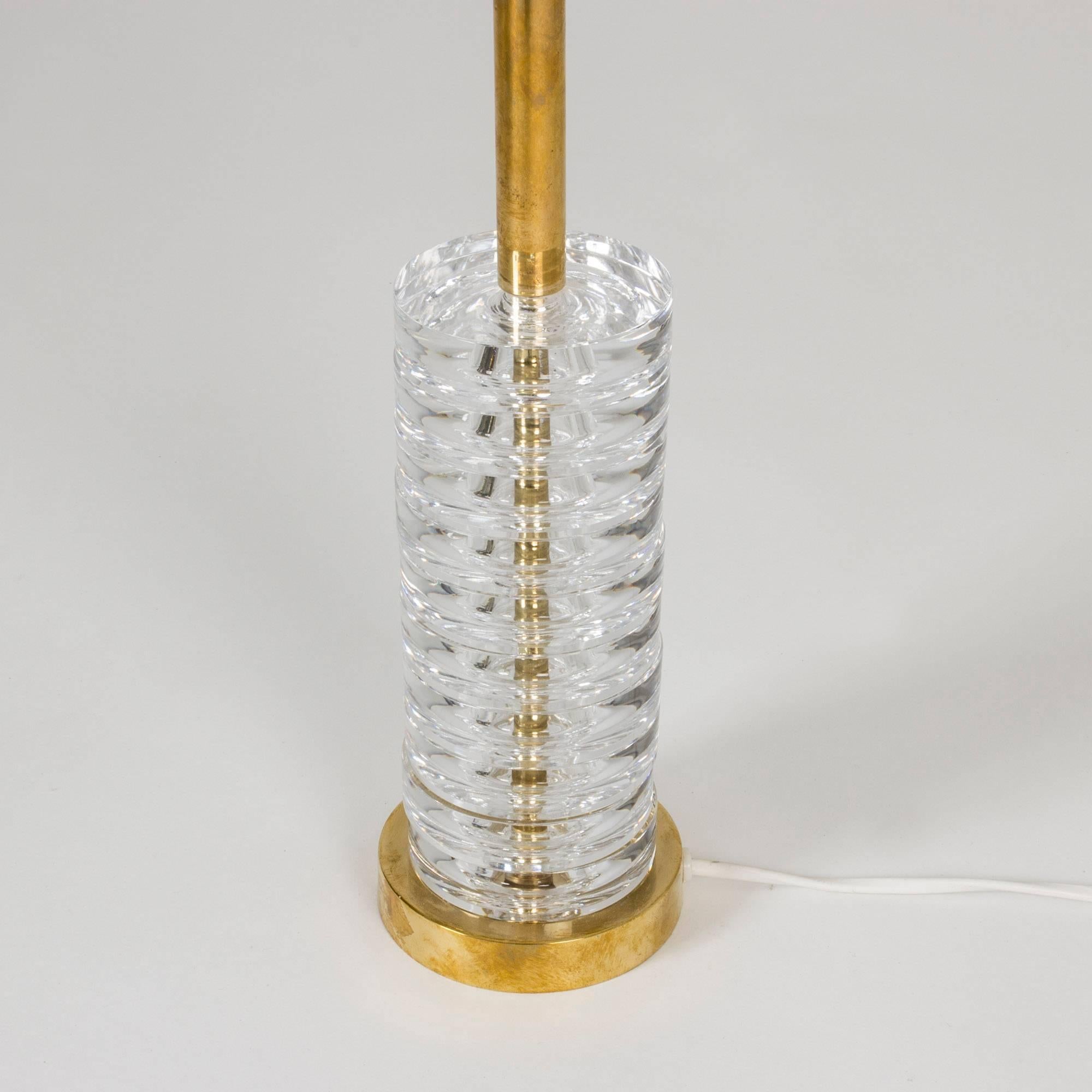 Delectably elegant brass and crystal table lamp by Carl Fagerlund. The base is made from thick, clear stacked crystal discs around a brass centre bar.
