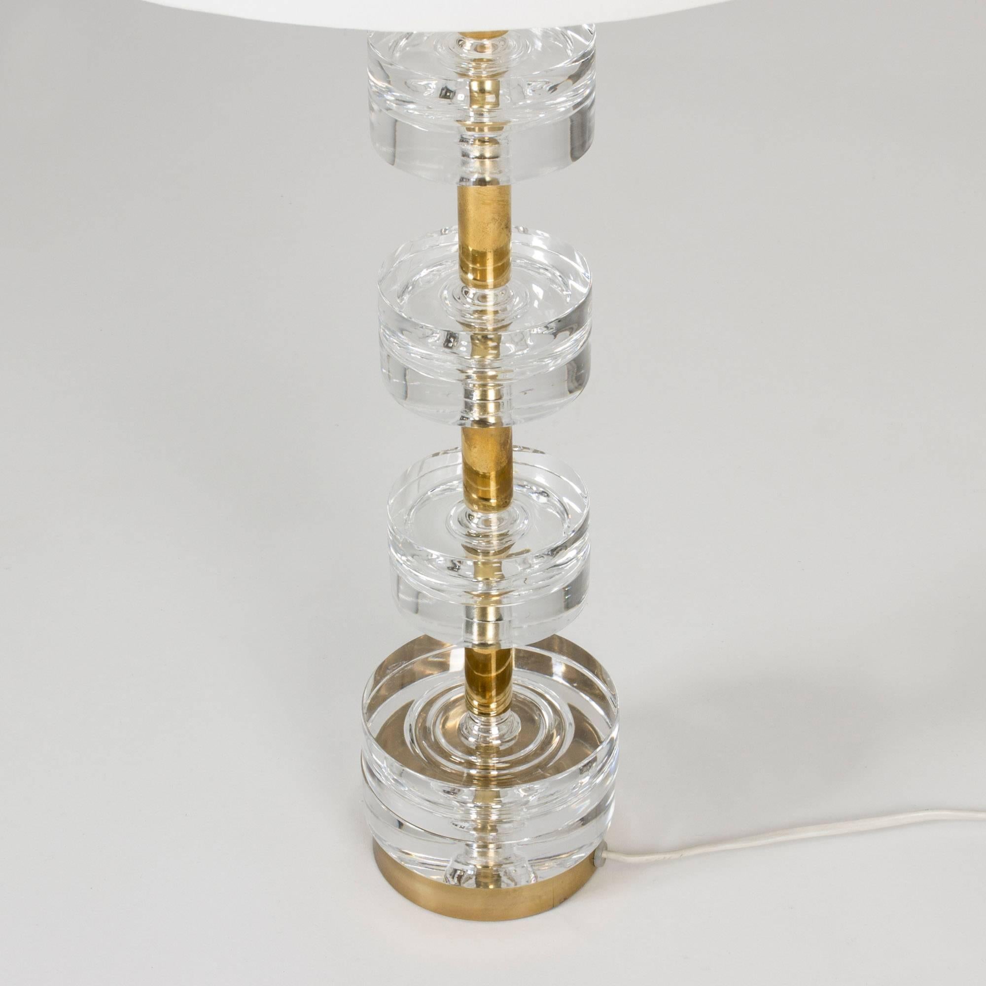 Delectably elegant brass and crystal table lamp by Carl Fagerlund. The base is made from four sets of thick, clear crystal discs around a brass centre bar.