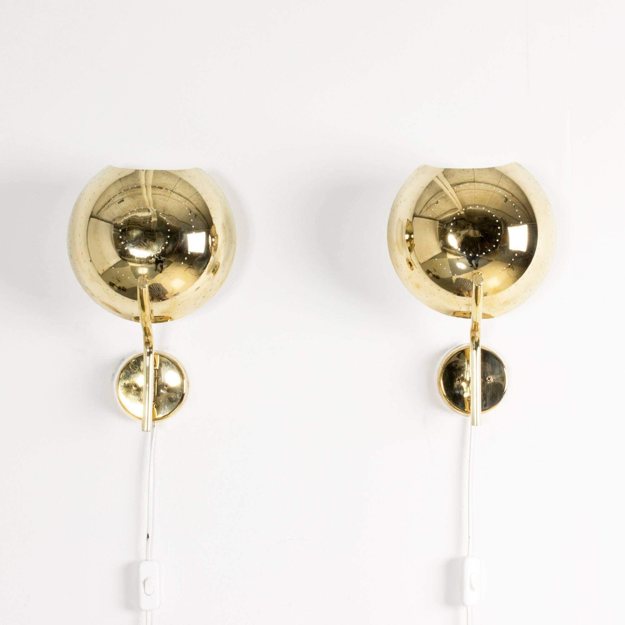 Pair of round Finnish brass wall sconces with a circular pattern of perforated holes. The tops of the sconces are slightly concave.