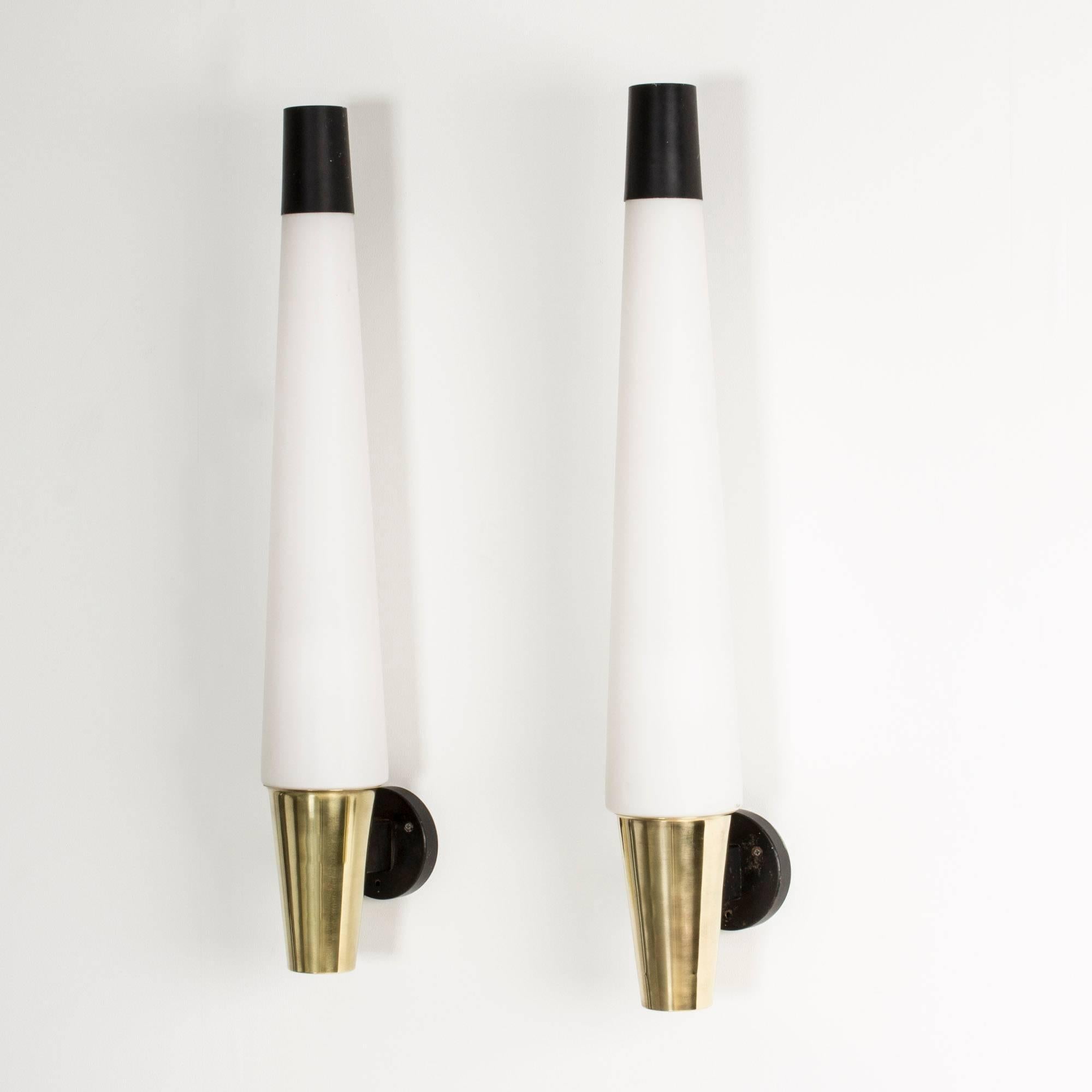Pair of amazing, oversized wall lamps, made in Sweden in the 1950s. Slightly cone shaped brass bases and opaline glass shades, topped off with black lacquered metal cups. Round, black lacquered metal wall fastenings.