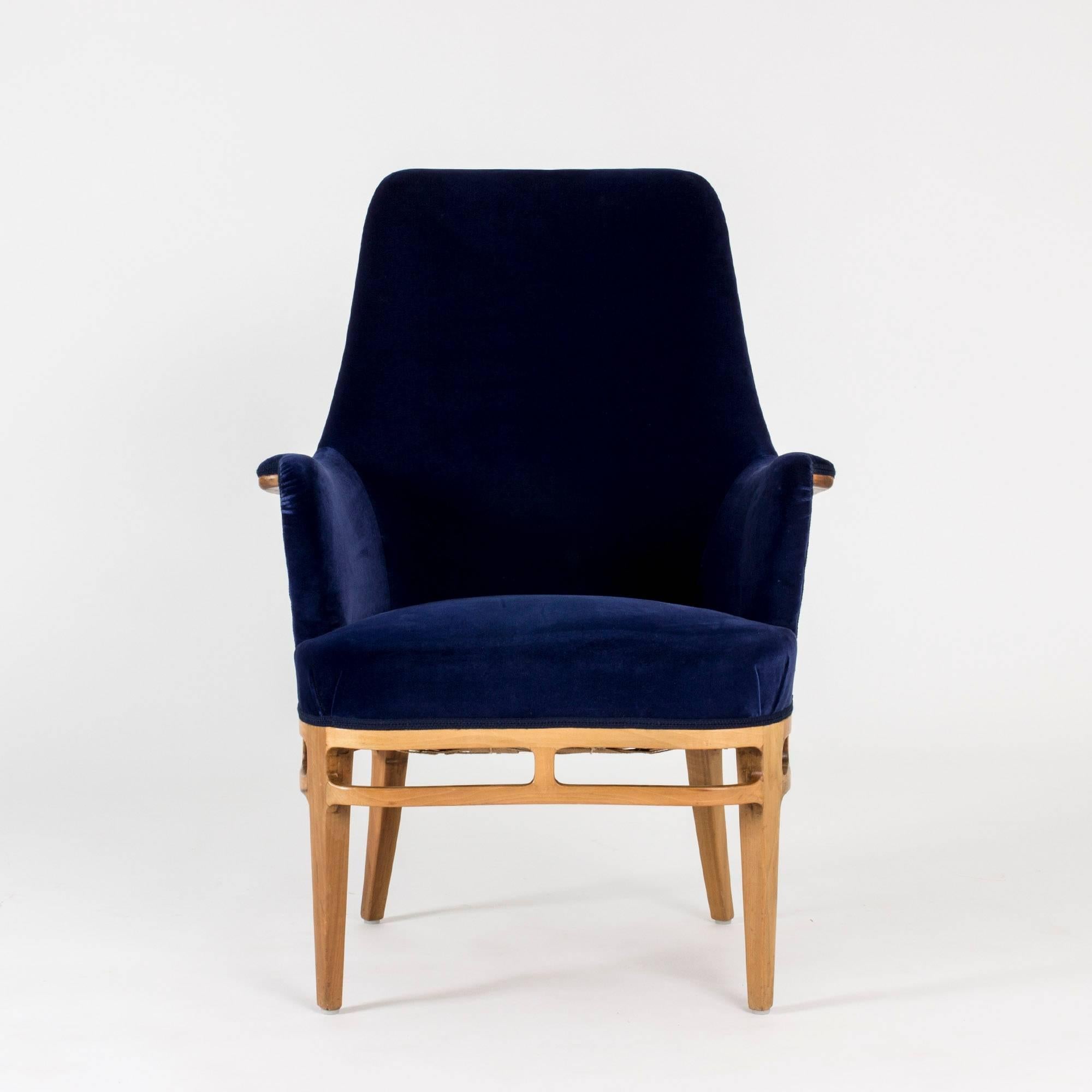 Exquisite lounge chair by Carl-Axel Acking, made in elmwood and upholstered with midnight blue velvet. Beautiful carved decor around the base of the seat and lines of wood following the curves of the armrests and back.