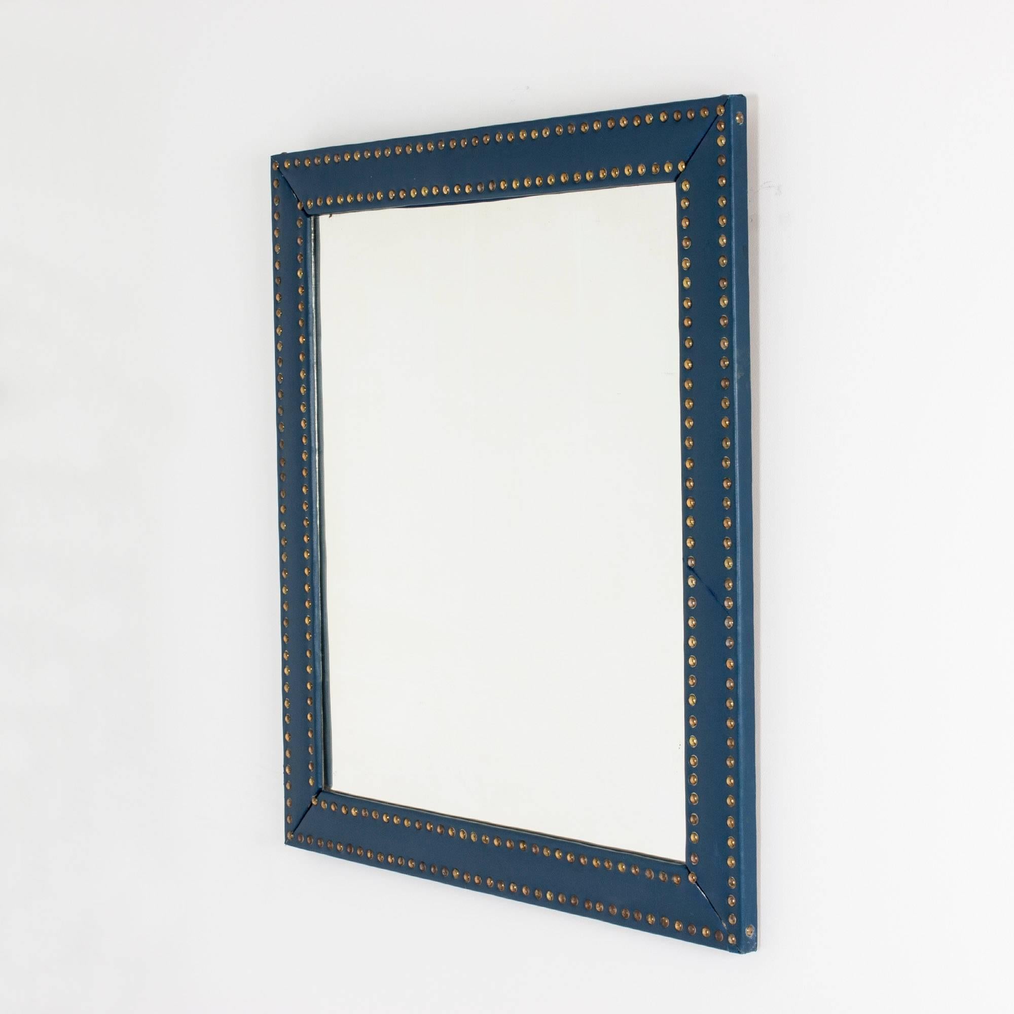 Large wall mirror by Otto Schulz. Frame dressed in dark blue faux leather, decorated with numerous brass nails. Nice combination of elegance and playfulness.