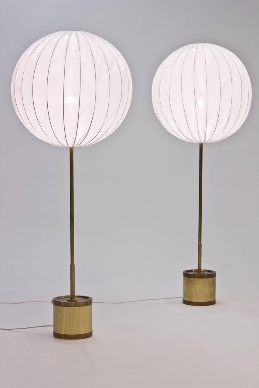 Pair of amazing brass floor lamps with large spherical white shades by Hans-Agne Jakobsson. The bases are heavy, making a great contrast to the lightness of the shades. A rare find!
