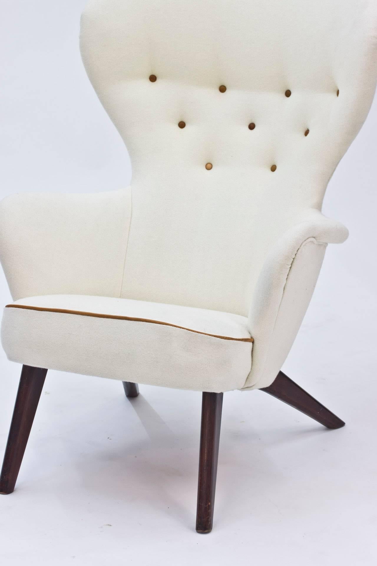 Awesome armchair by Finnish designer Gustaf Hiort af Ornäs, made in the 1950s. Neatness and edginess in a perfect combination. Stained wooden legs, white Kvadrat upholstery with cognac colored leather details.