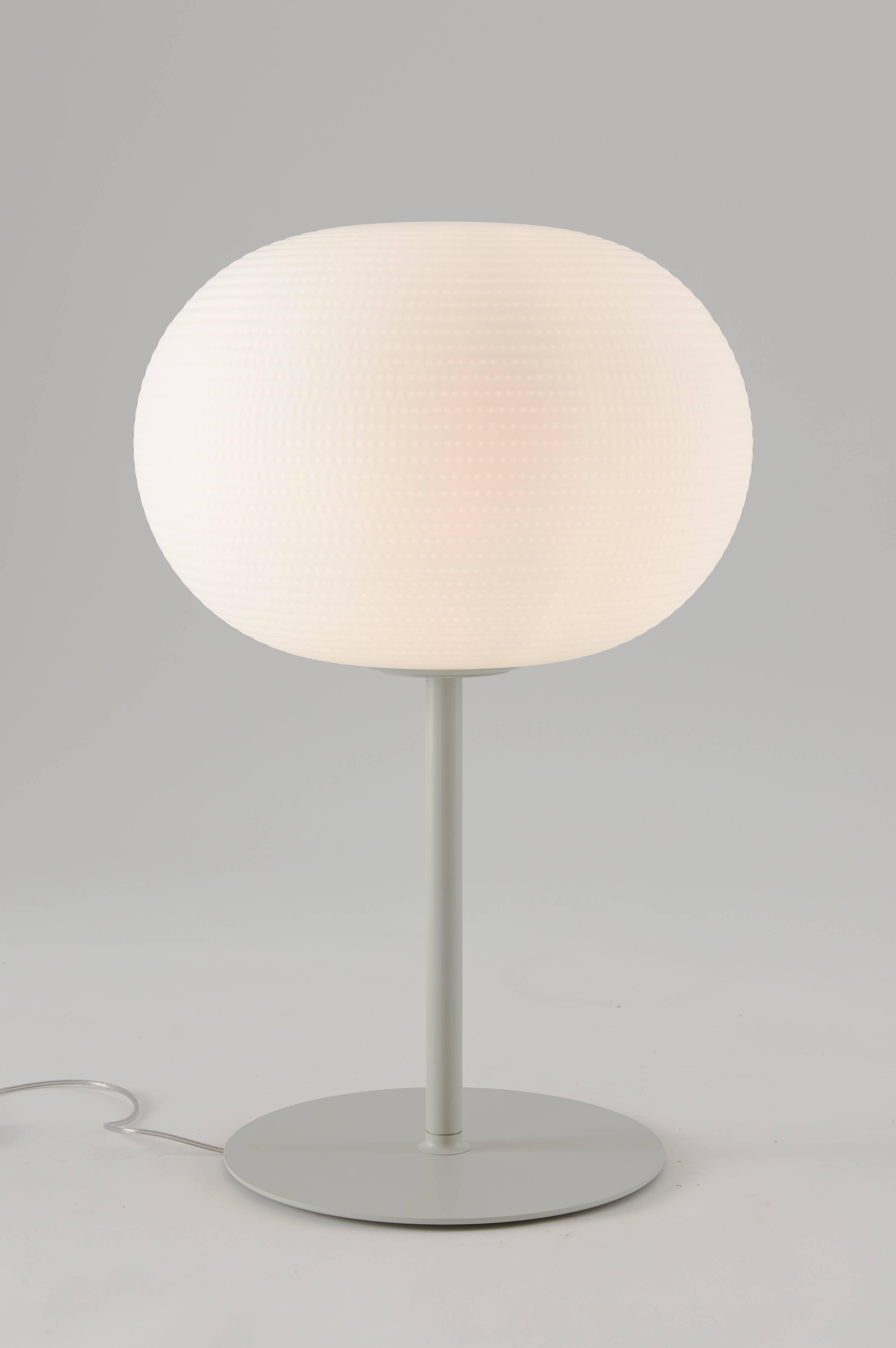 Bianca medium table lamp with stem by Matti Klenell from Fontana Arte. 

Its beautifully balanced shape is enriched and made unique by an orderly series of delicate, light grooves that, on the white volume of the glass, look like tiny prints on