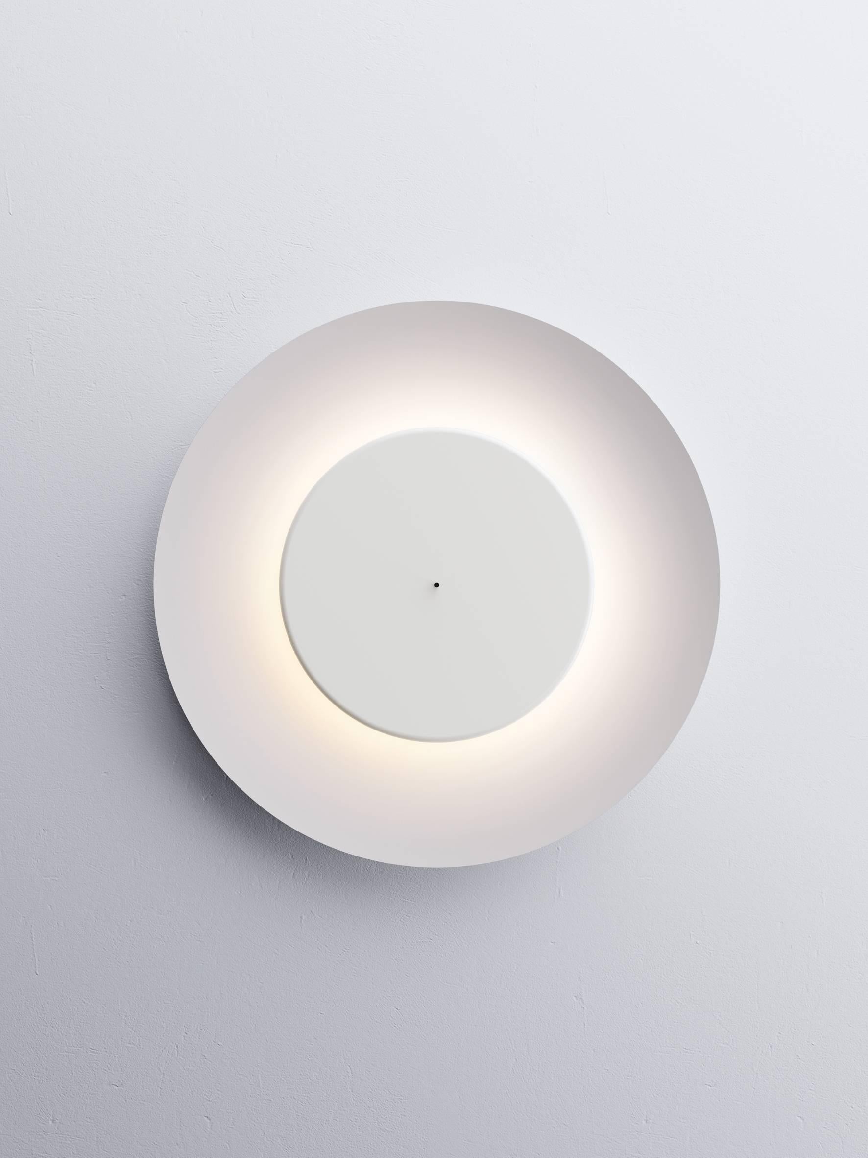 A wall and ceiling lamp with a surprising light effect, reminiscent of the phenomenon produced by eclipses. The light produced depends on the position of the smaller front disc containing the light source with regard to the large concave aluminum