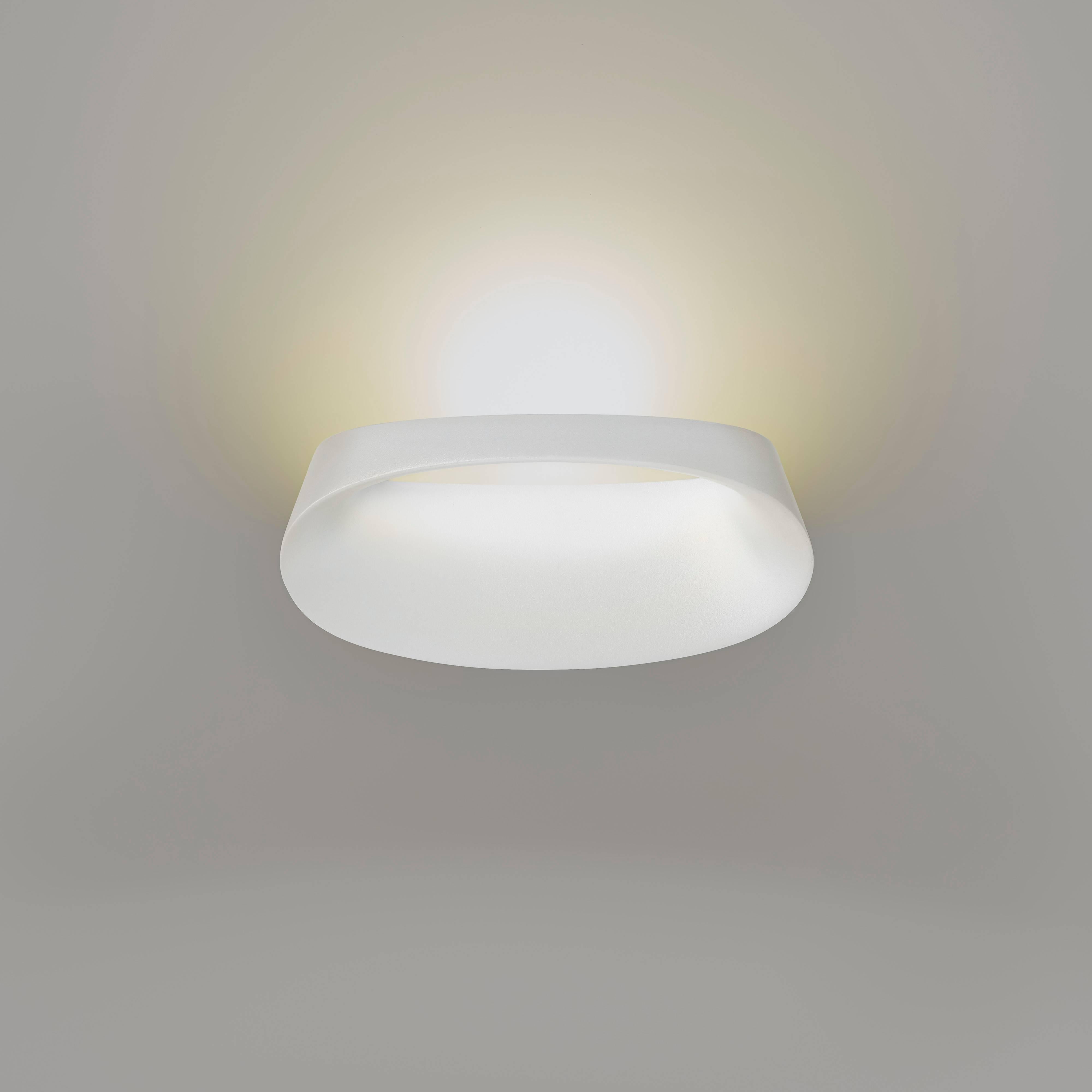 Manufactured in 2017 by Fontana Arte and designed by Odo Fioravanti in 2014, the Bonnet wall lamp in white die-cast aluminum reworks the concept of indirect lighting. The top part conceals a small yet very powerful Led source whose ray of light is