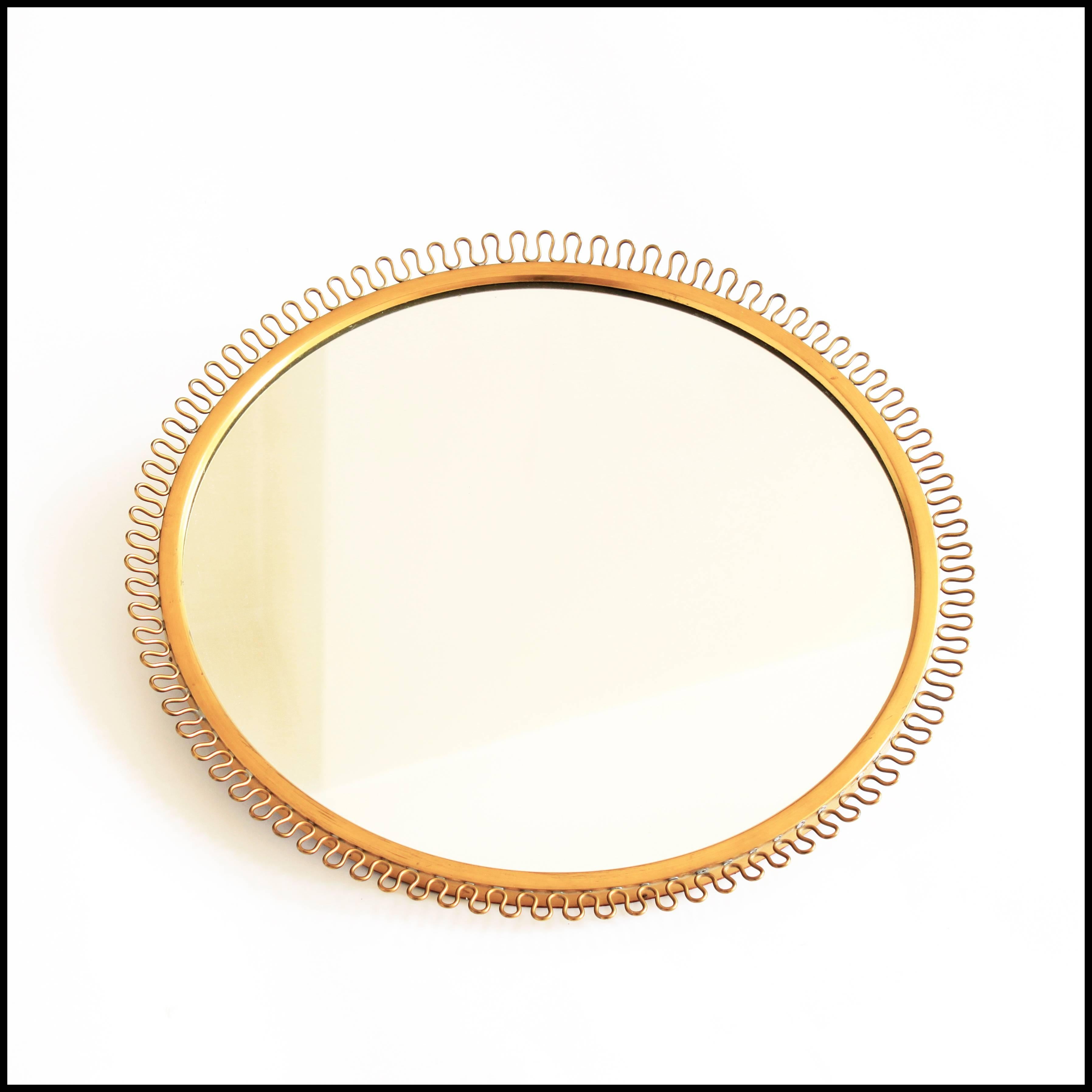 A brass wall mirror with a decorative corona edge, designed in Sweden by Josef Frank for Svenskt Tenn in the 1940s.