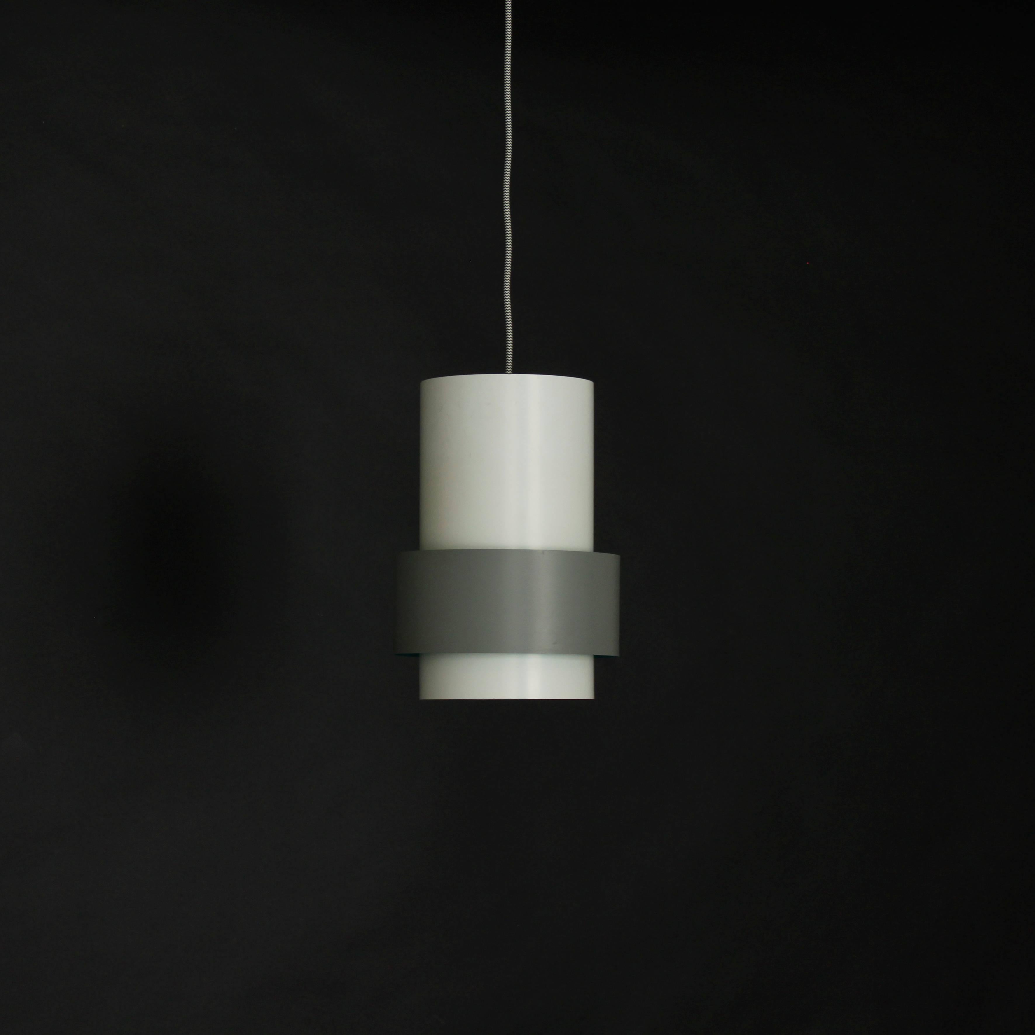 A cylindrical suspension lamp designed in Denmark by Jo Hammerborg for Fog & Morup. White lacquered steel with grey lacquered outer band inside which the metal is lacquered eu de nil green producing a subtle presence of color when illuminated.