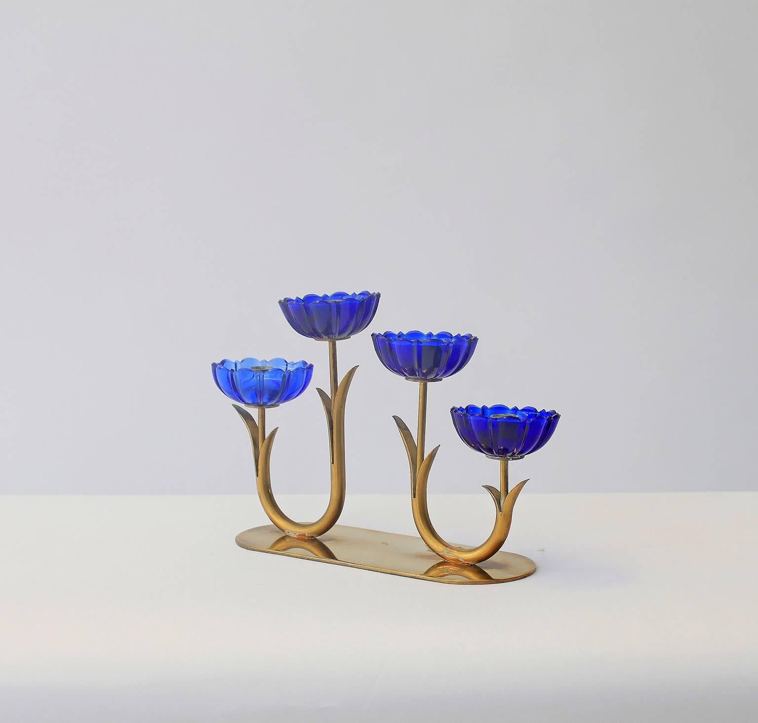 A blue flower candleholder from Sweden comprising four blue glass flowers on aged, patinated, gold-plated brass stems. Designed by Gunnar Ander for Ystad Metall.
 