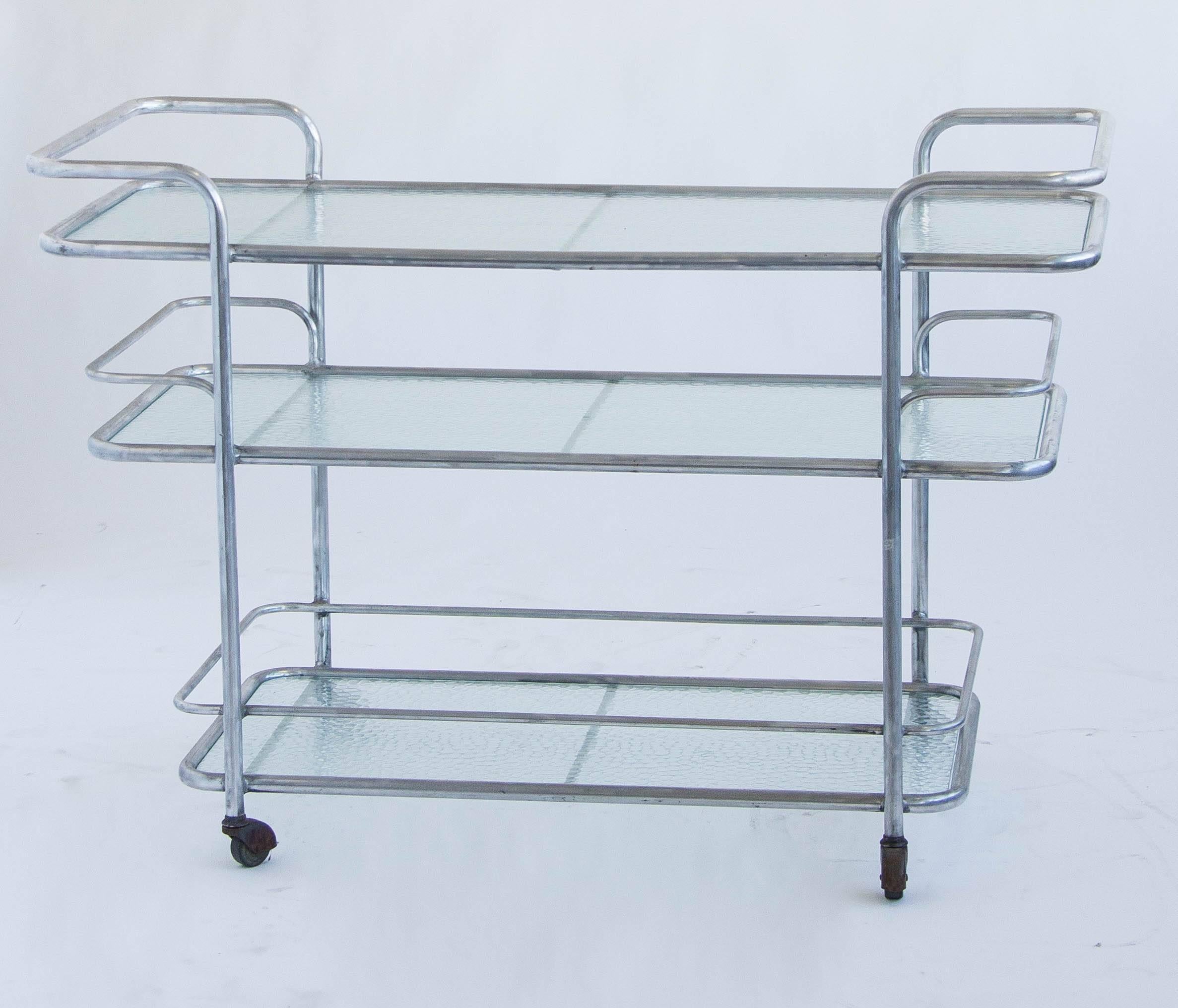 The bar cart was designed for Brown Jordan's classic outdoor collections in the 1970s. Its clean, handsome lines are constructed of brushed aluminum and dimpled, translucent glass.