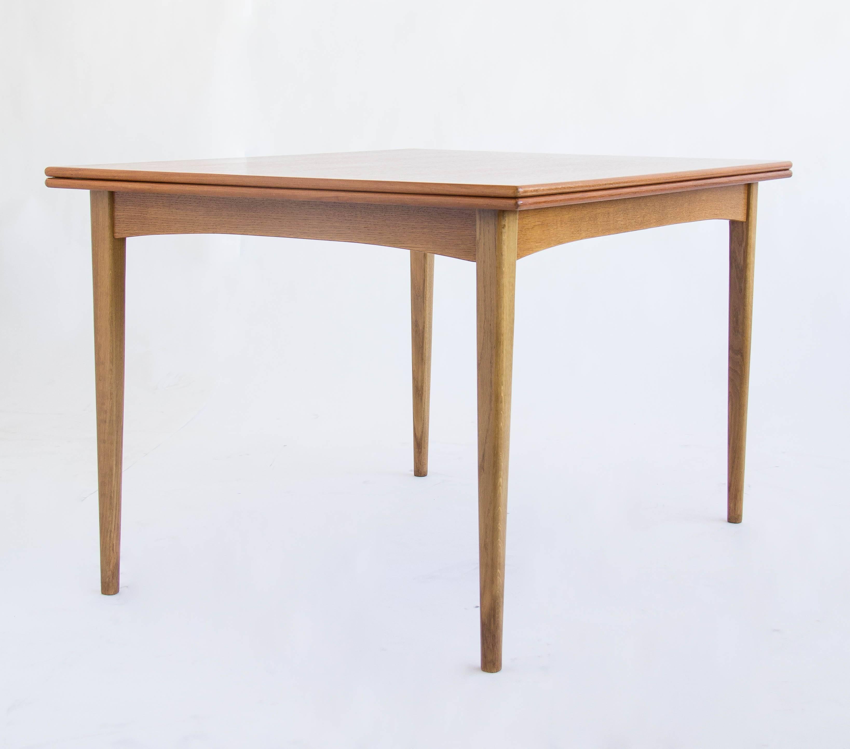 This is a incredible dining table designed by Folke Ohlsson for Dux of Sweden. The teak top has a swivel mechanism that allows it to rotate 90 degrees, and the top will then unfold.
The table completely transforms as the original length becomes the