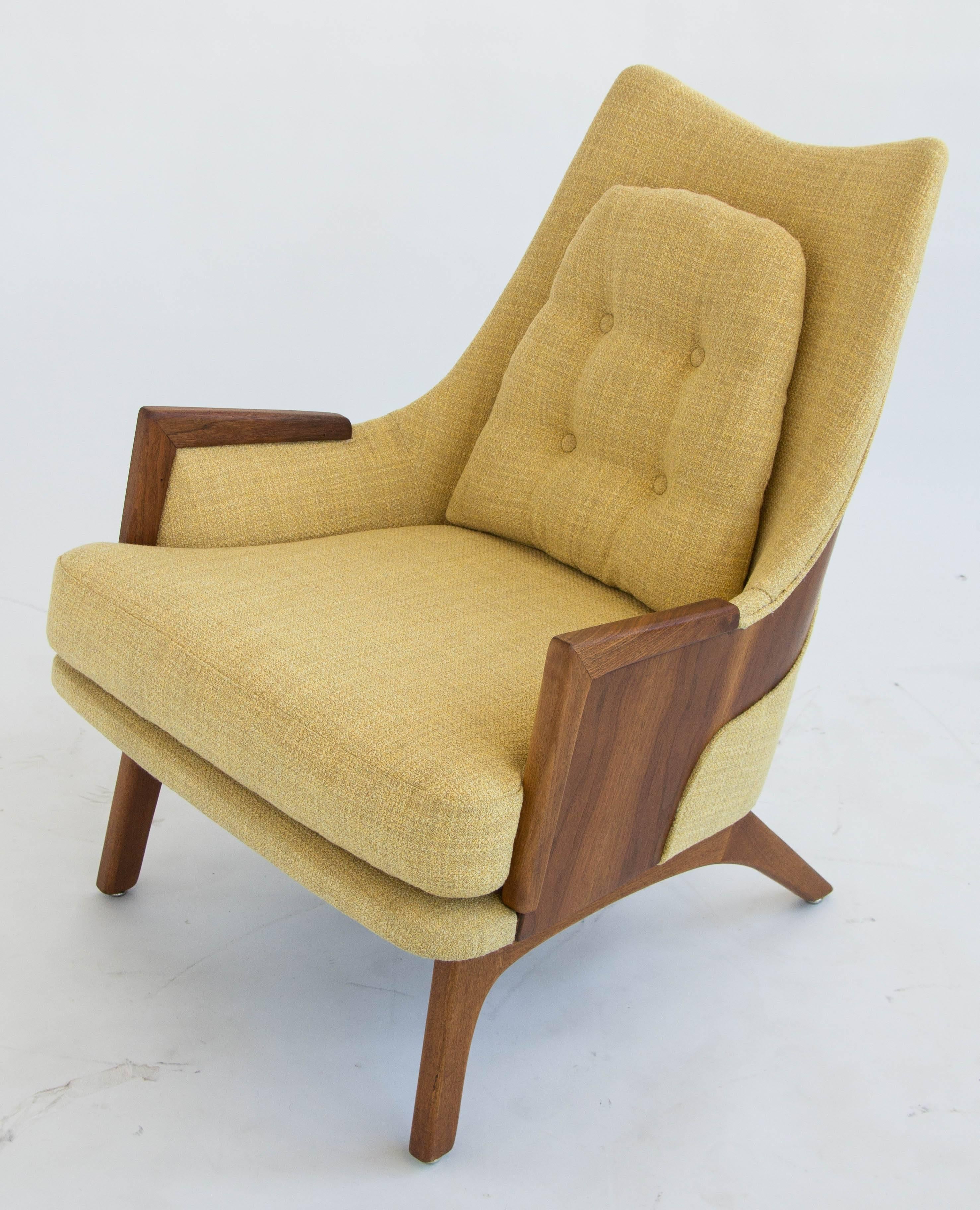 This lounge chair features a distinctive “wrapped” detail, where the walnut wood frame is exposed in a sculpted band across the backside of the chair.  The piece was reupholstered in a butter yellow tweed that contrasts beautifully with the