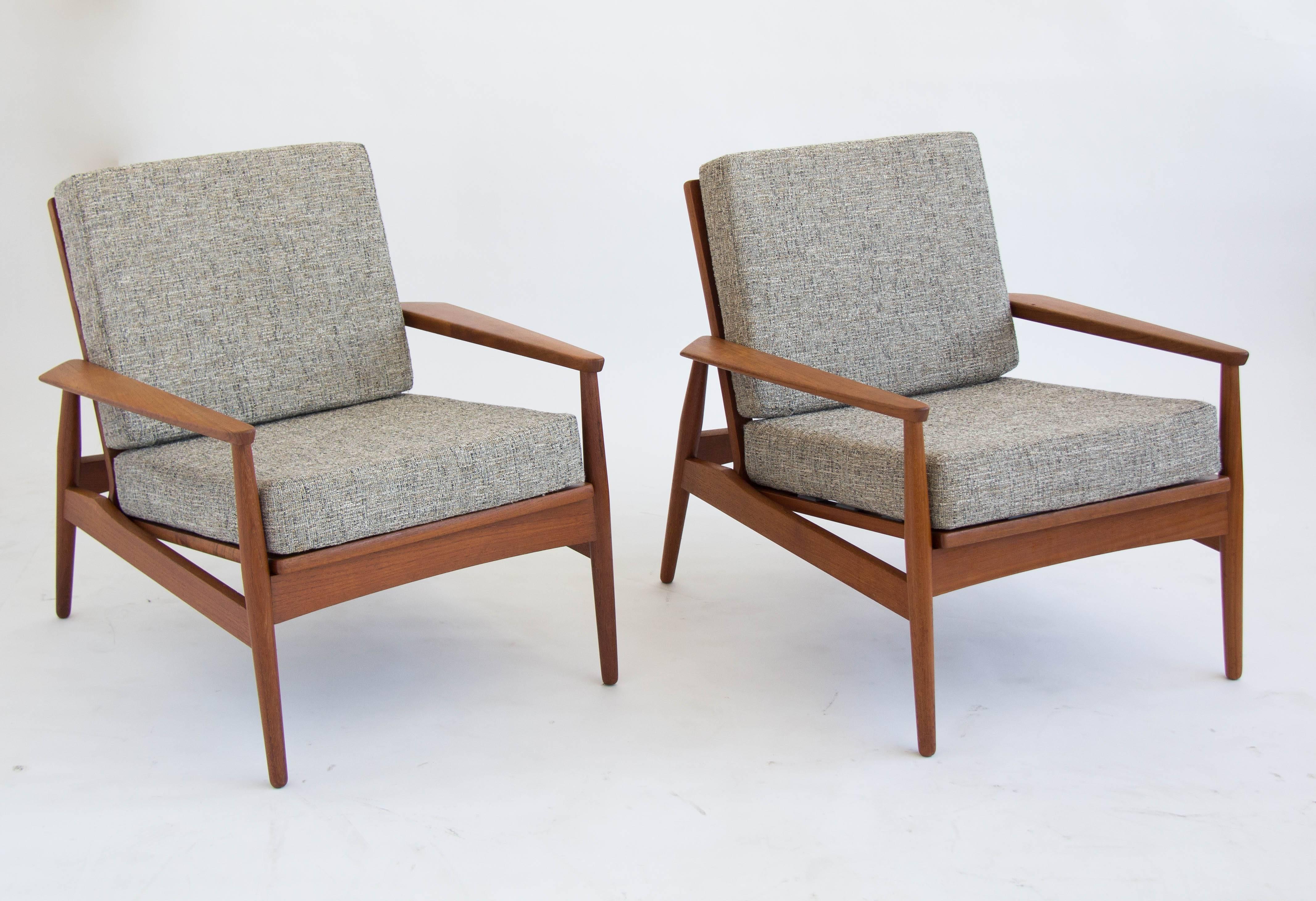 Matched pair of teak Danish modern lounge chairs with sculpted armrests.  The foam backrest and seat cushions recline at an angle to the main frame and are upholstered in a salt-and-pepper tweed.  
The chairs are stamped 