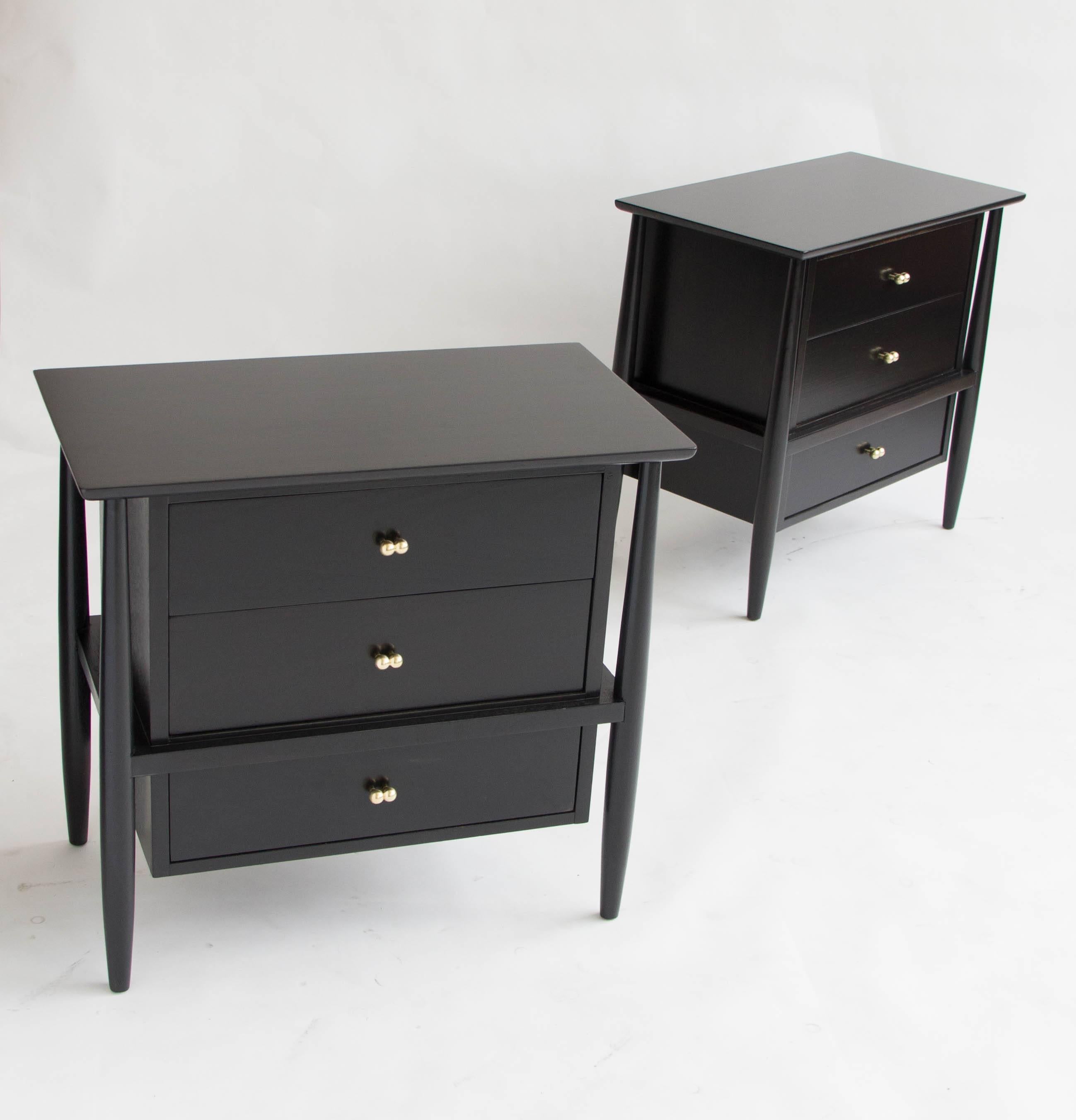 A pair of elegantly designed nightstands sold by John Stuart and manufactured by Mt. Airy. Each piece has four exposed legs that suspend a floating three-drawer stack in ebonized walnut, with rich wood grain on full display. Each drawer opens with a