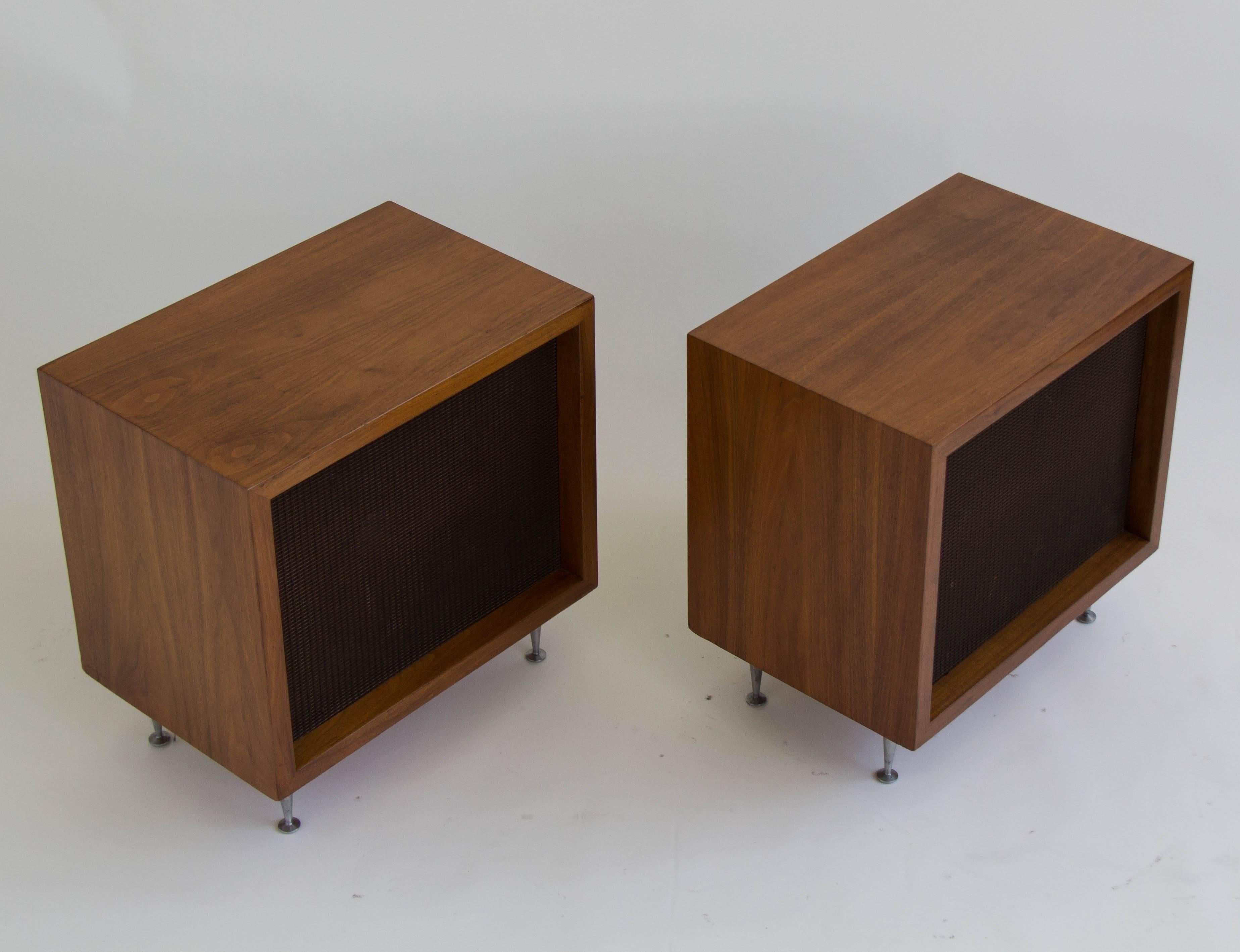 A pair of JBL (James B Lansing) speakers in Baron C38 walnut cases designed by Alvin Lustig. Each speaker sits a top four brushed aluminum legs with flat glides. Back panel hardware bears the JBL name. Speakers are in good working order.