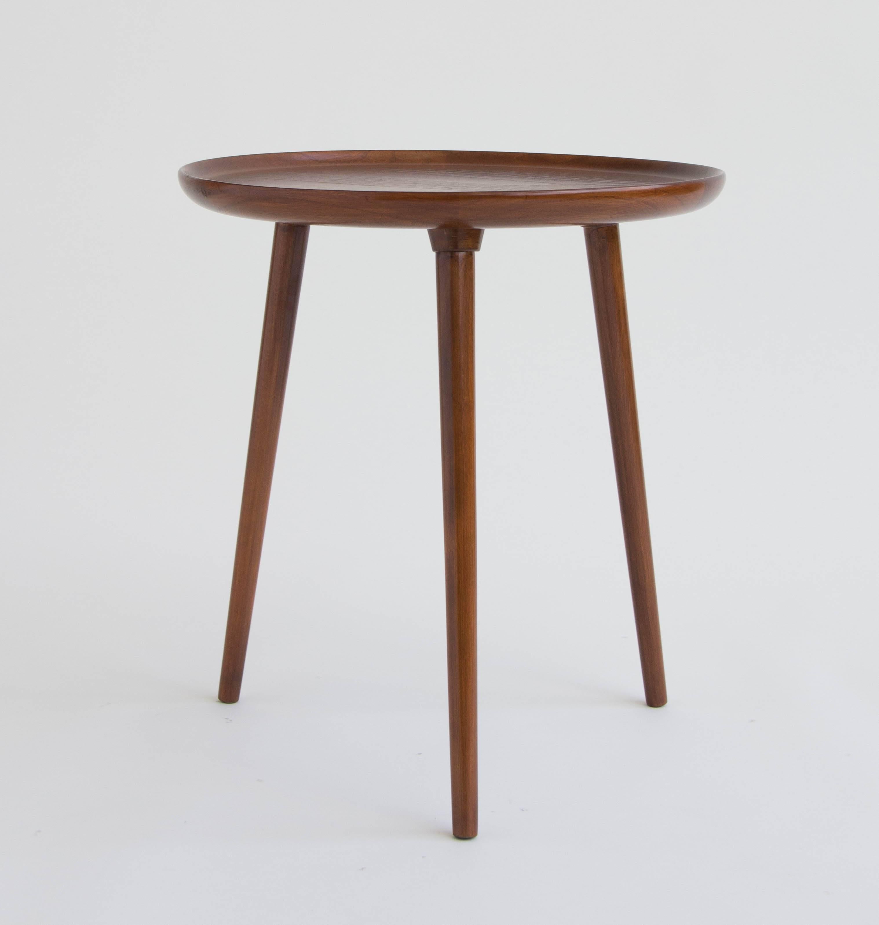 A round side table with three legs. Designed for Selig of Denmark, the piece is made of solid walnut, with tapered legs and slightly raised edges around the table top for a bowl effect. Stamped “Made in Denmark” on the underside of table.