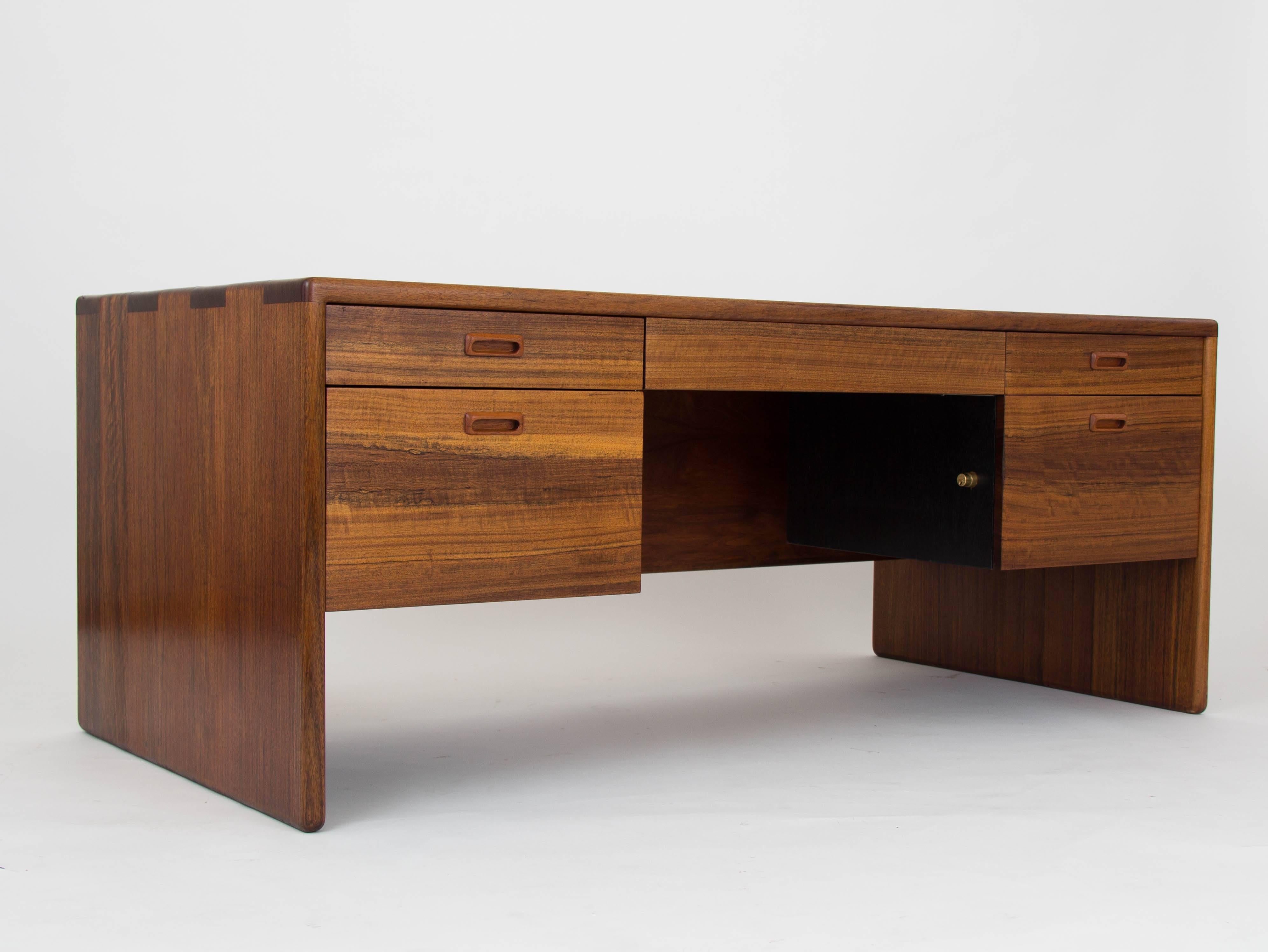 A large executive desk by Southern California designer Gerald McCabe for his own company Erin Furniture. The piece, executed in a deep brown Shedua wood, has a simple case with exaggerated finger joints and rounded corners. A modesty panel covers
