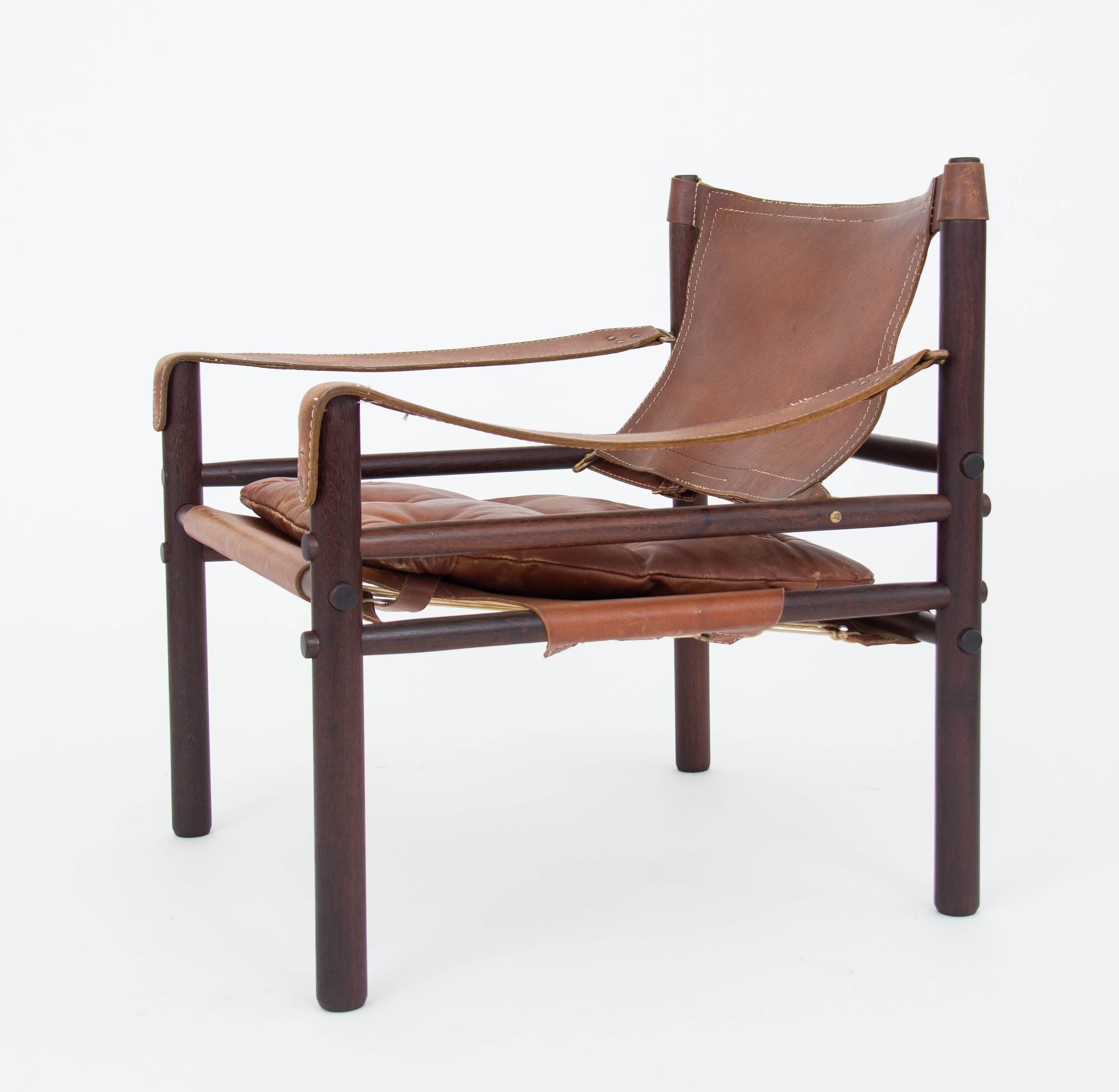 An example in chocolate brown leather of the 'Sirocco' safari chair designed by Arne Norell for his eponymous company, Norell Möbel AB of Småland, Sweden. The chair features a solid rosewood frame strapped together by leather slings with brass