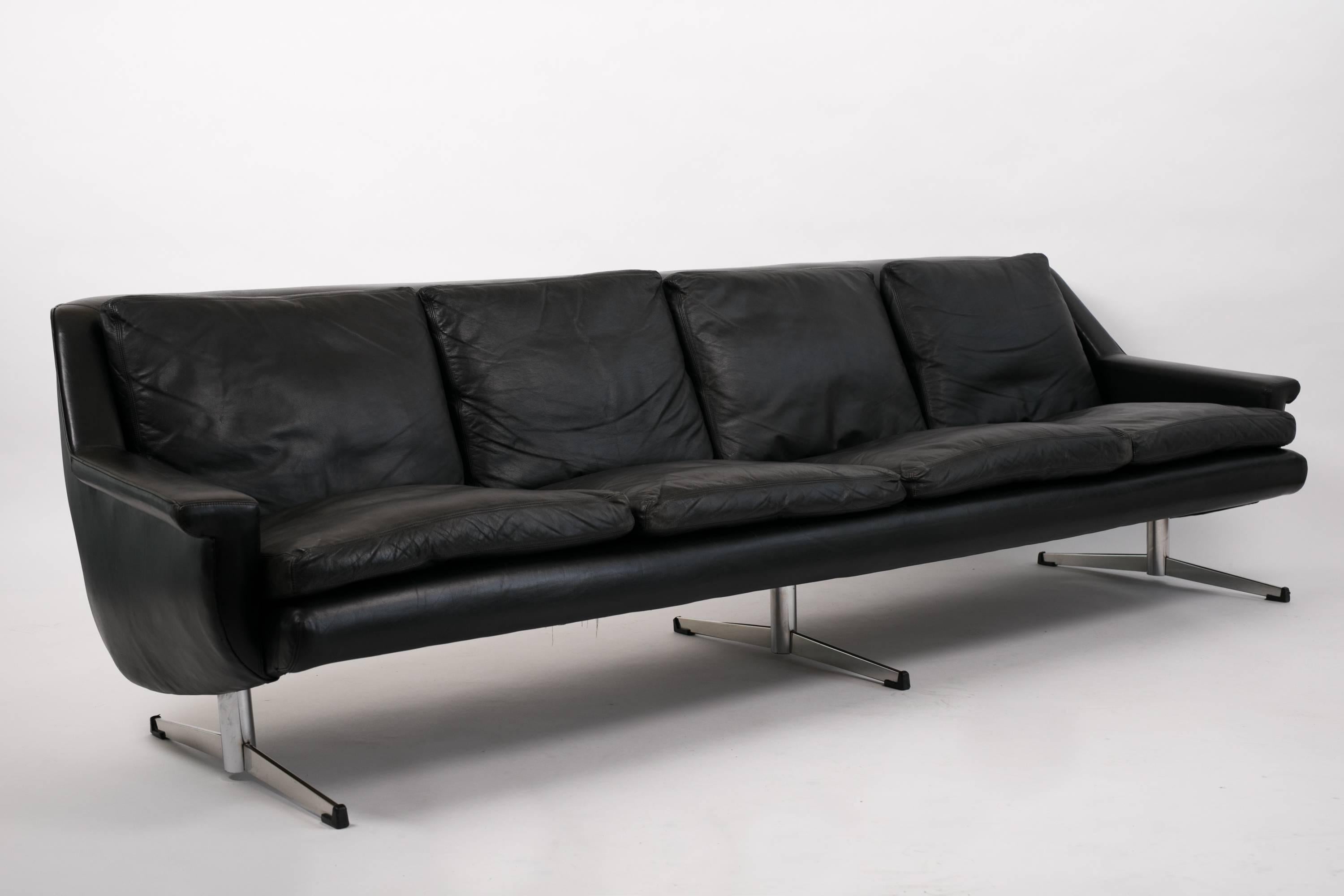 A long Danish modern sofa in beautifully worn black leather designed by Georg Thams for Vejen Polstermøbelfabrik. This example has four seats with removable back and seat cushions, held in a molded case upholstered in matching leather. The flat