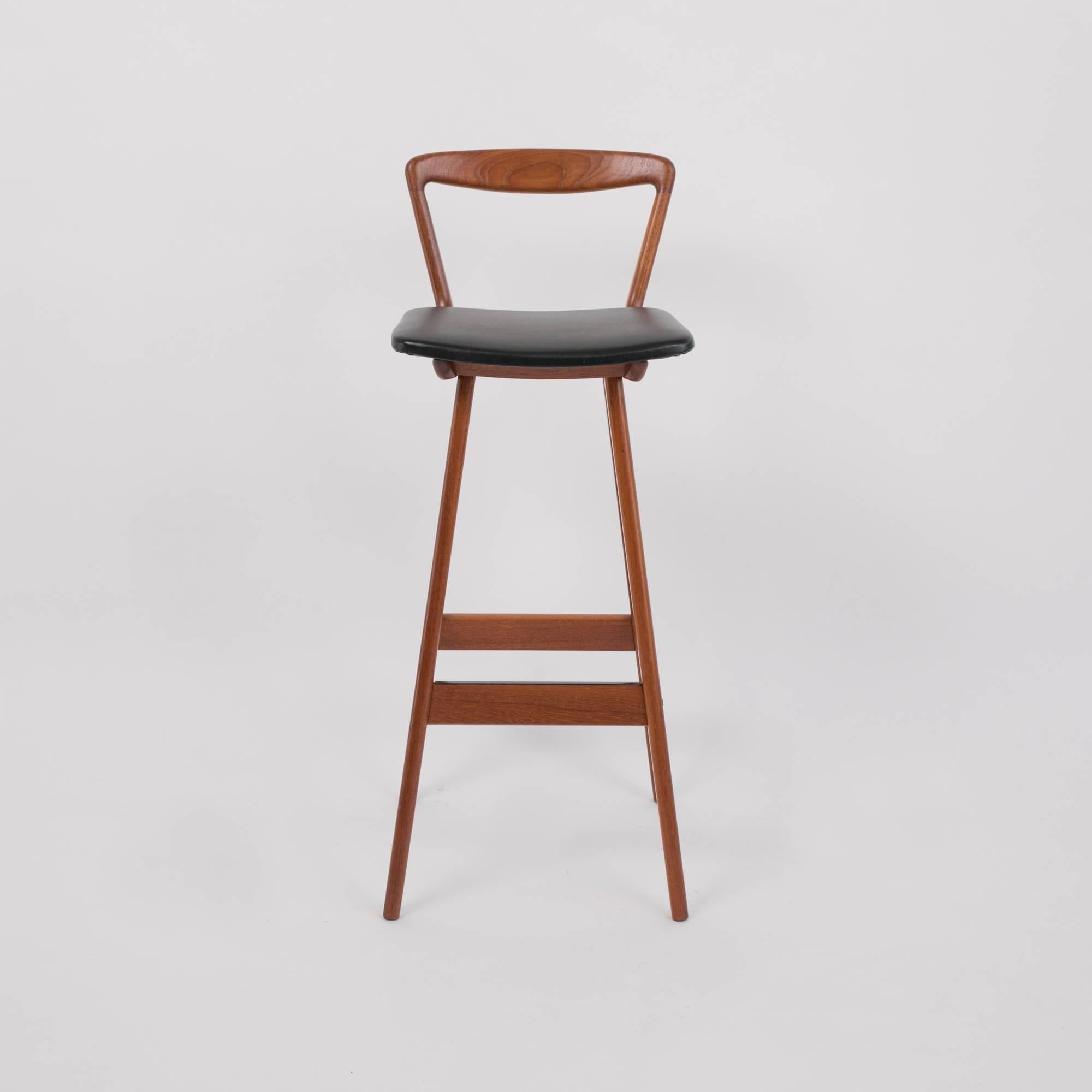 A set of four 1960s bar stools by Henry Rosengren Hansen for Brande Møbelindustri. The stools have their original vinyl-upholstered seats and sit on frames of solid teak. Each stool has flat, tapered legs and an open backrest. The horizontal