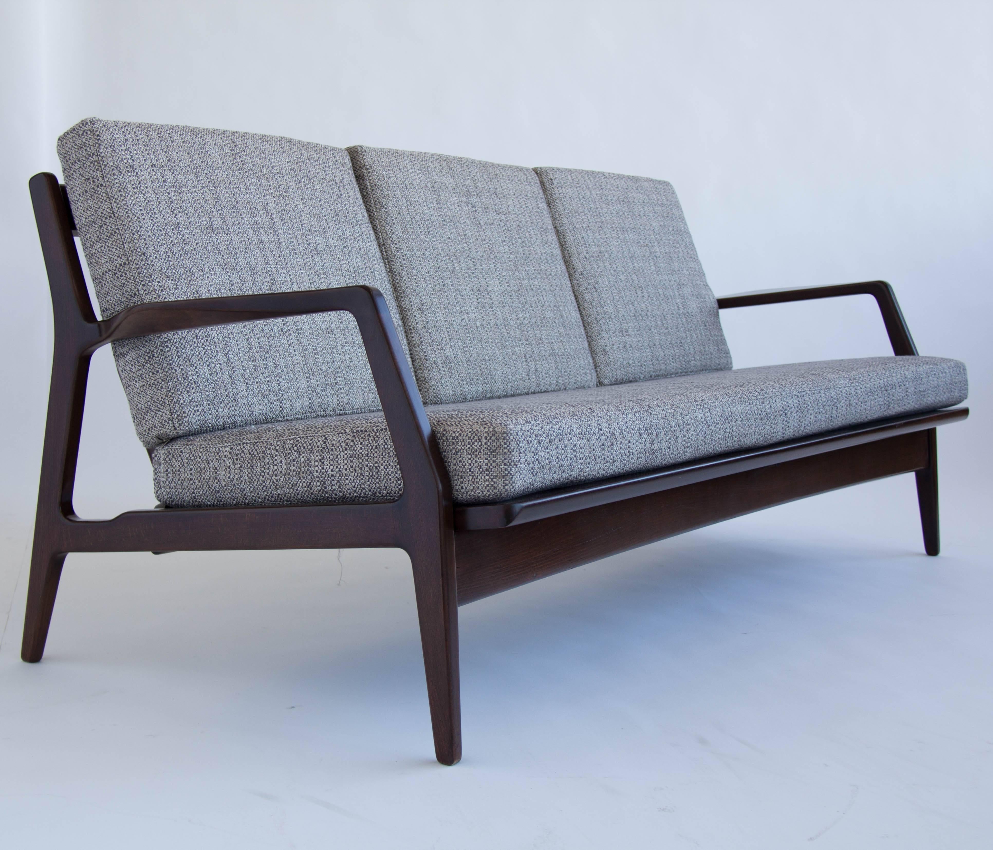 Danish modern sofa by Ib Kofod-Larsen for Selig. Sculptural solid frame with a walnut finish. The frame has been fully restored. The upholstery, foam and straps that holds up the seat have been replaced.