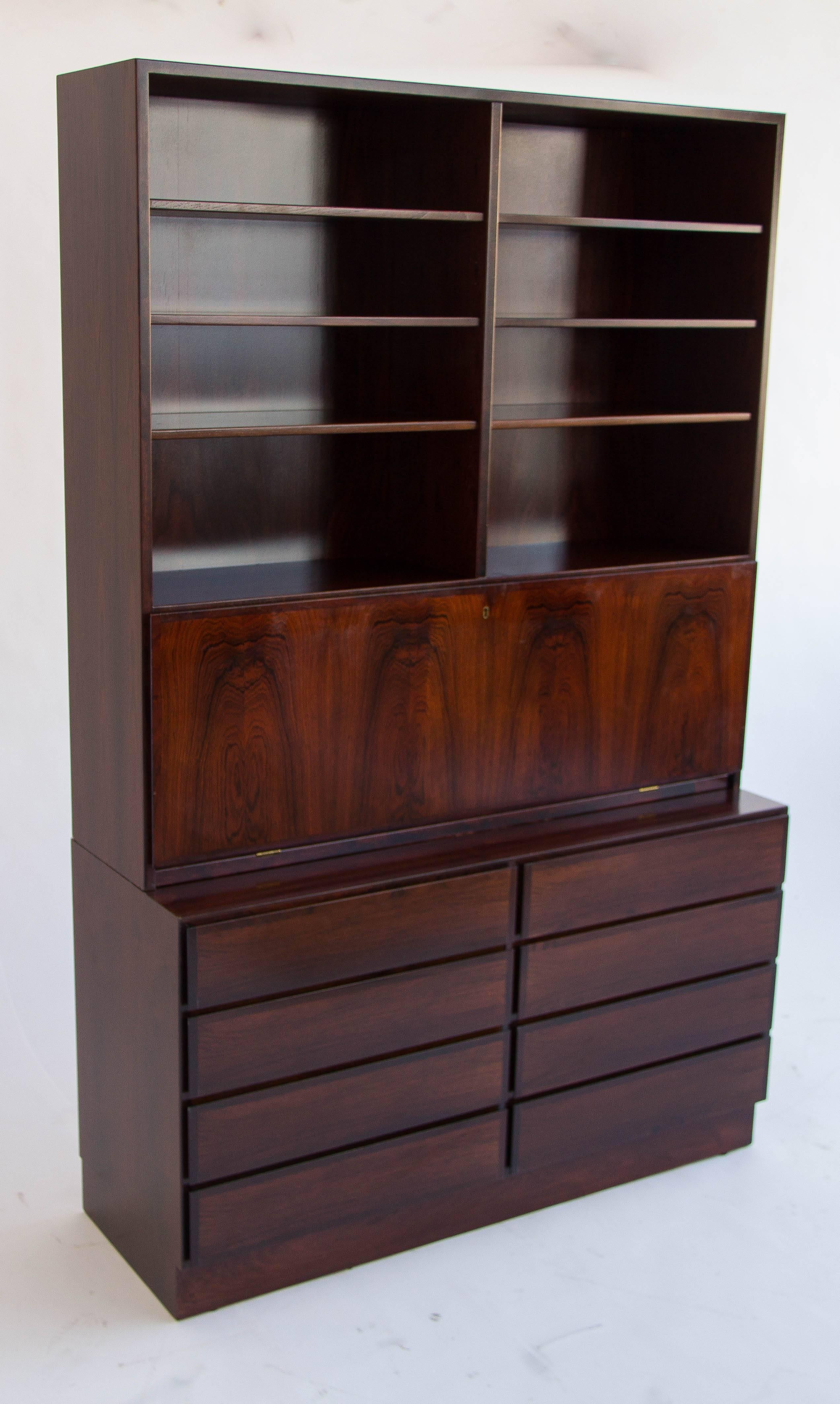 This is an incredible rosewood desk by Gunni Oman for Oman Jun made in Denmark. The bottom half is comprised of eight drawers with a birch interior. The top portion features a locking fold-down secretary desk. Also within that compartment are seven